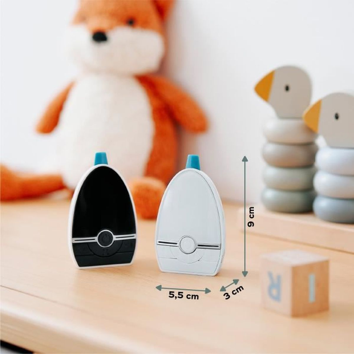Zwei Babyphone auf einem Tisch, ein Stofffuchs, Holzspielzeug. Ein Monitor ist schwarz, einer weiß.