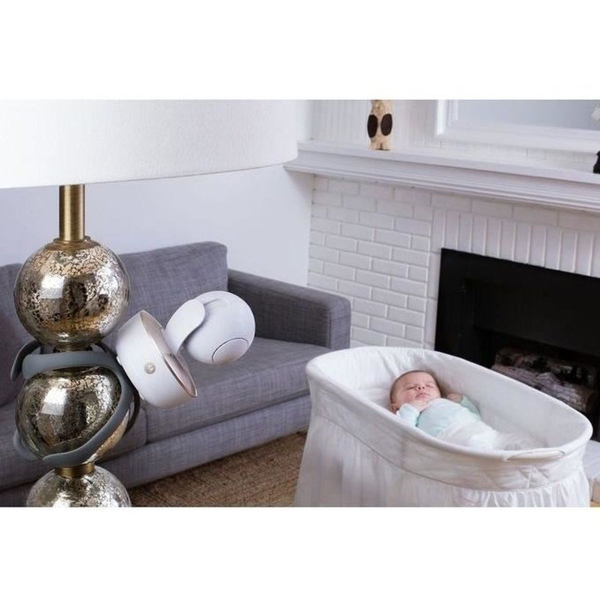 Babyphone auf einer Lampe, mit einem Baby in einem Babybett. Die Lampe hat dekorative Kugeln.