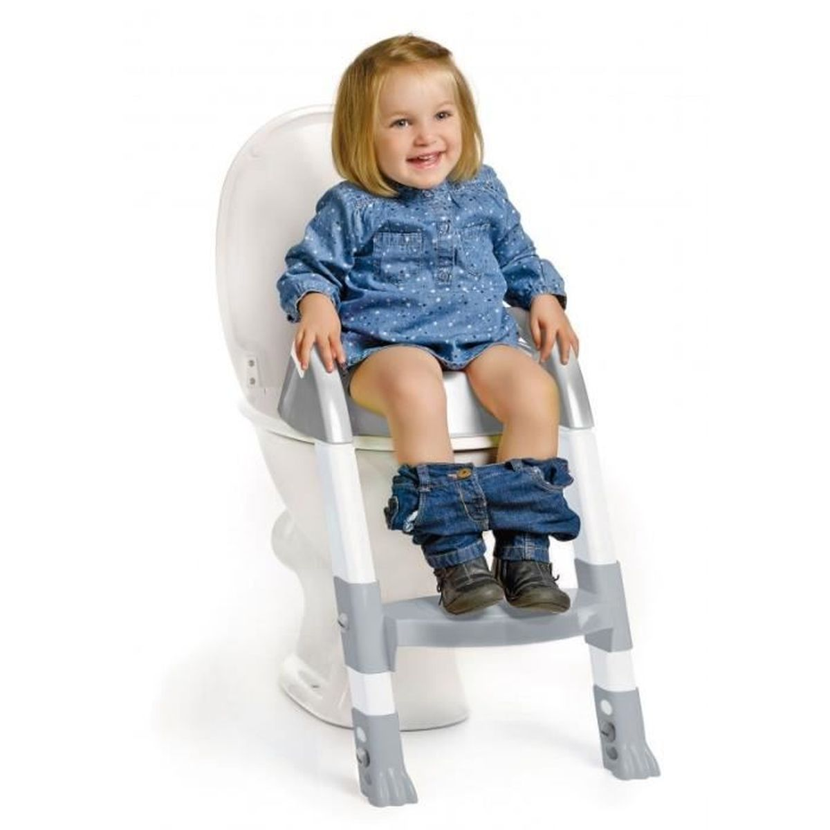 Ein kleines Mädchen sitzt mit einem Tritthocker auf einer Toilette. Sie lächelt und trägt Jeans.