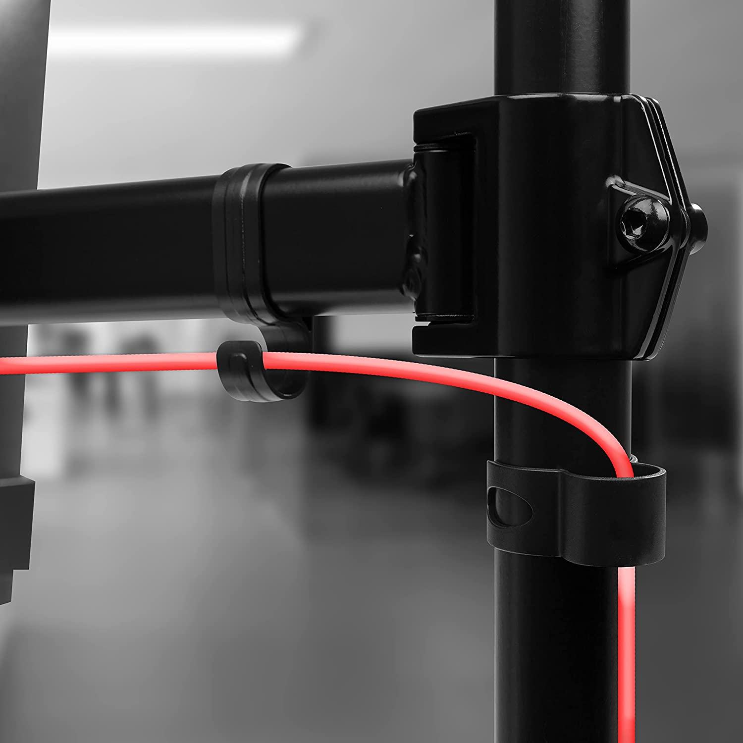 Nahaufnahme eines schwarzen Metallständers. Ein rotes Kabel wird von Klammern gehalten.
