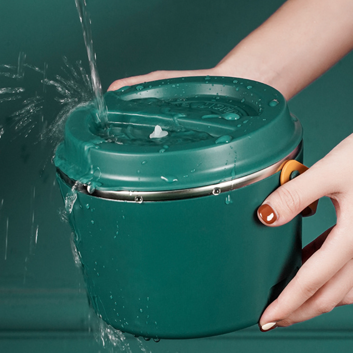 Ein grüner Lunchbehälter, der mit Wasser gefüllt wird. Der Behälter hat einen Griff.
