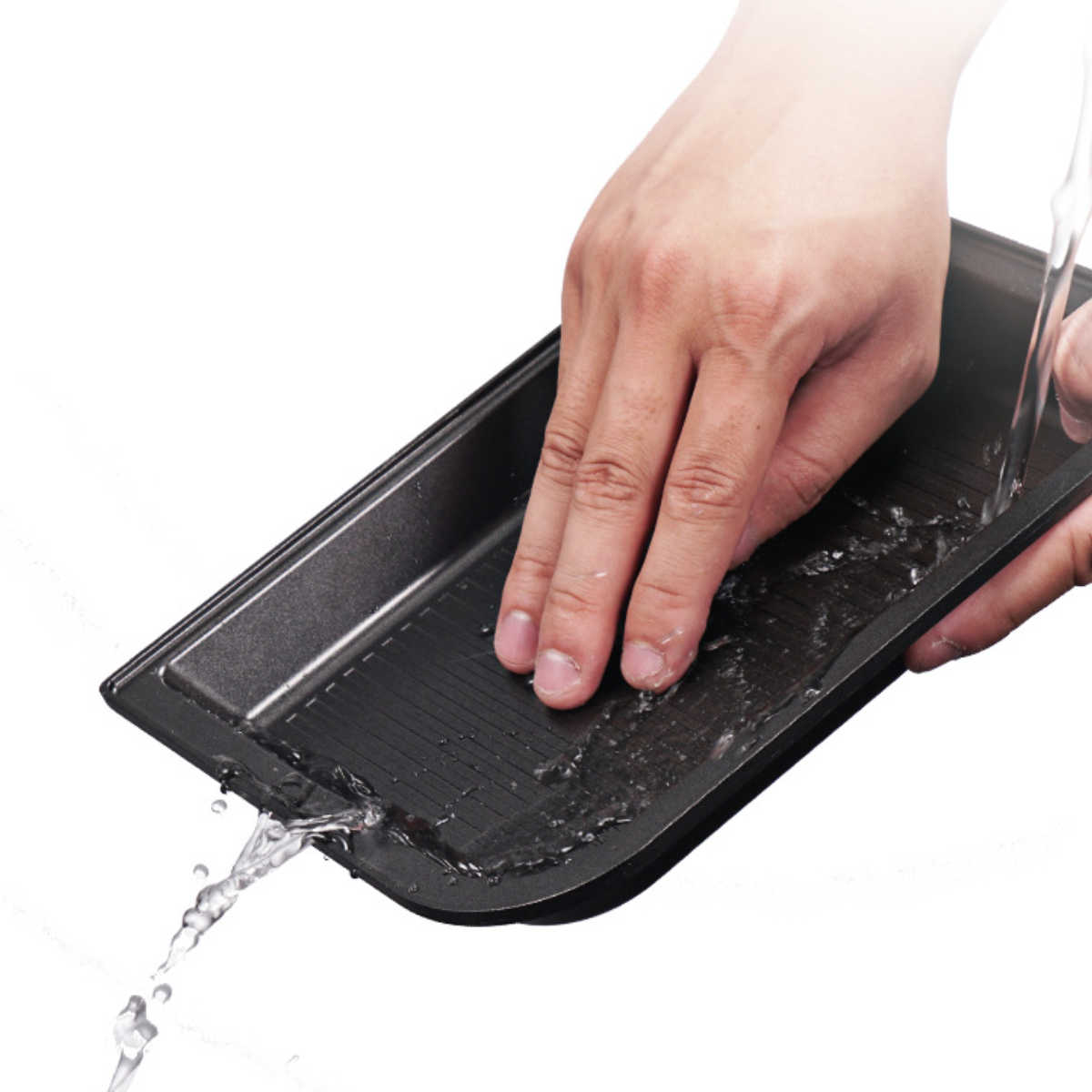 Hand wäscht eine schwarze Autokonsolenablage mit Wasser. Wasser fließt aus dem Wasserhahn.