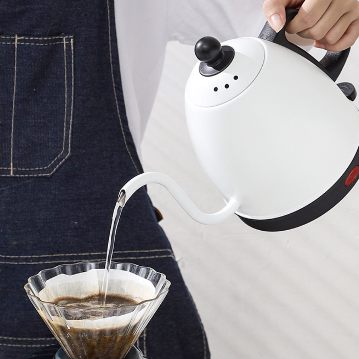 Weißer Wasserkocher gießt Wasser in einen Glas-Kaffeezubereiter.
