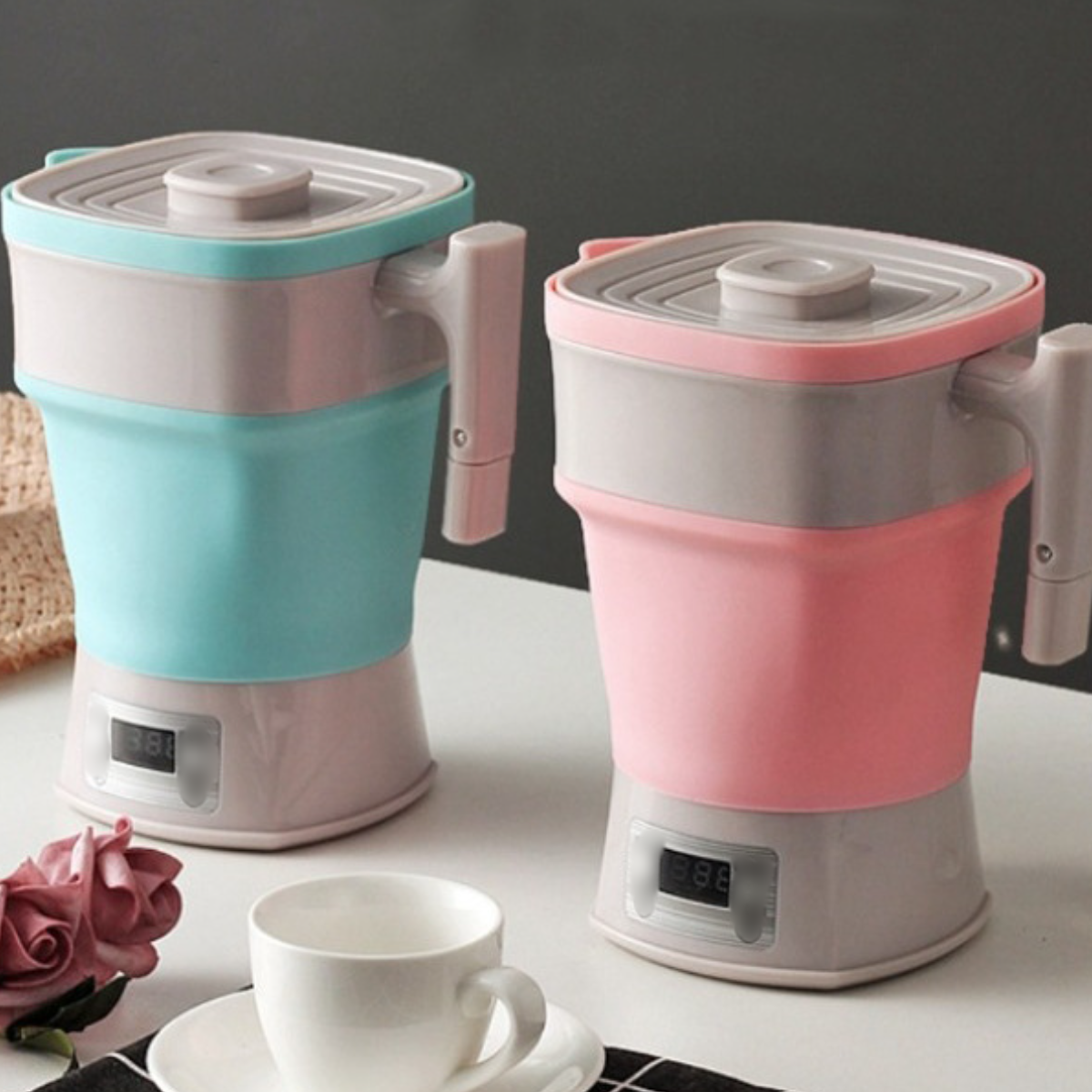 Zwei faltbare elektrische Wasserkocher, einer rosa und einer blau, mit Digitalanzeigen.
