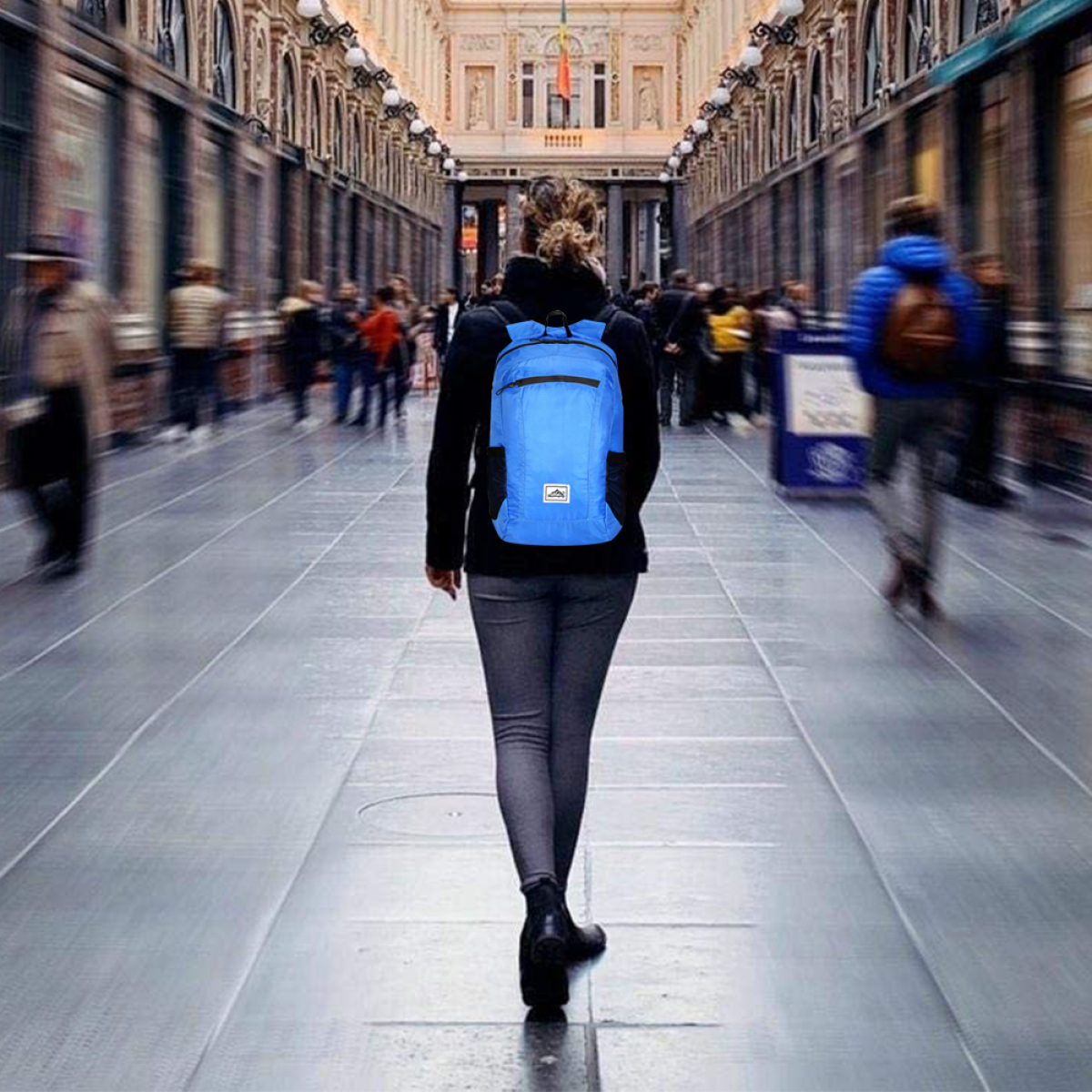 Eine Person, die in einem Einkaufszentrum mit einem blauen Rucksack geht.