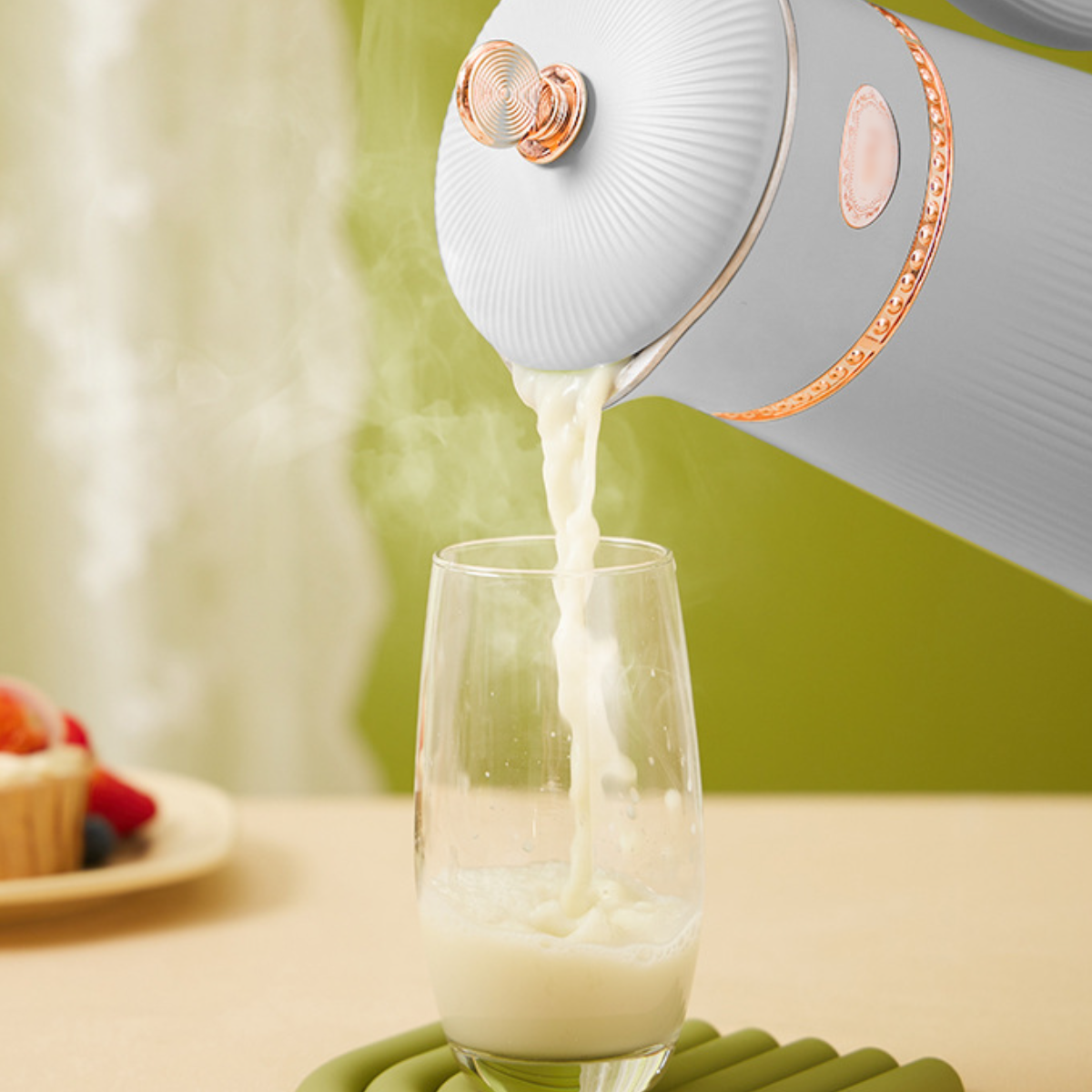 Weiß-grauer Wasserkocher gießt einen Flüssigkeitsstrahl in ein Glas.