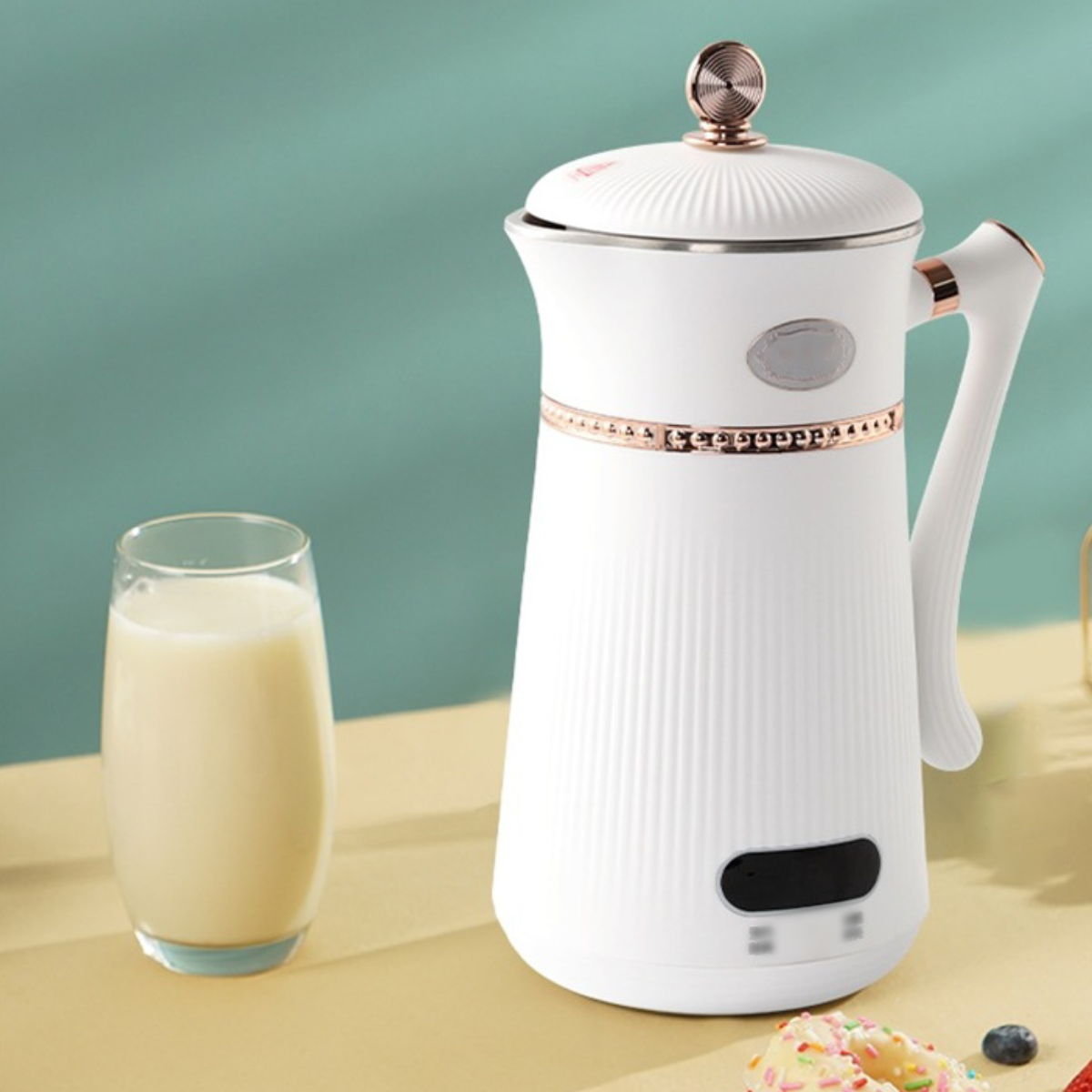 Weißer elektrischer Wasserkocher mit roségoldfarbener Verzierung und Glas Milch.