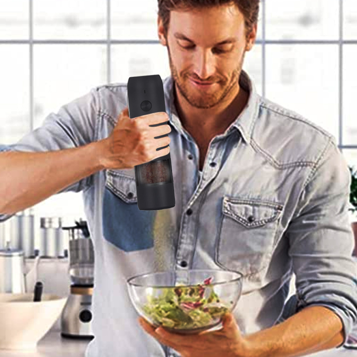 Ein Mann in einer Küche, der Pfeffer über eine Salatschüssel mahlt, mit einer schwarzen Pfeffermühle.