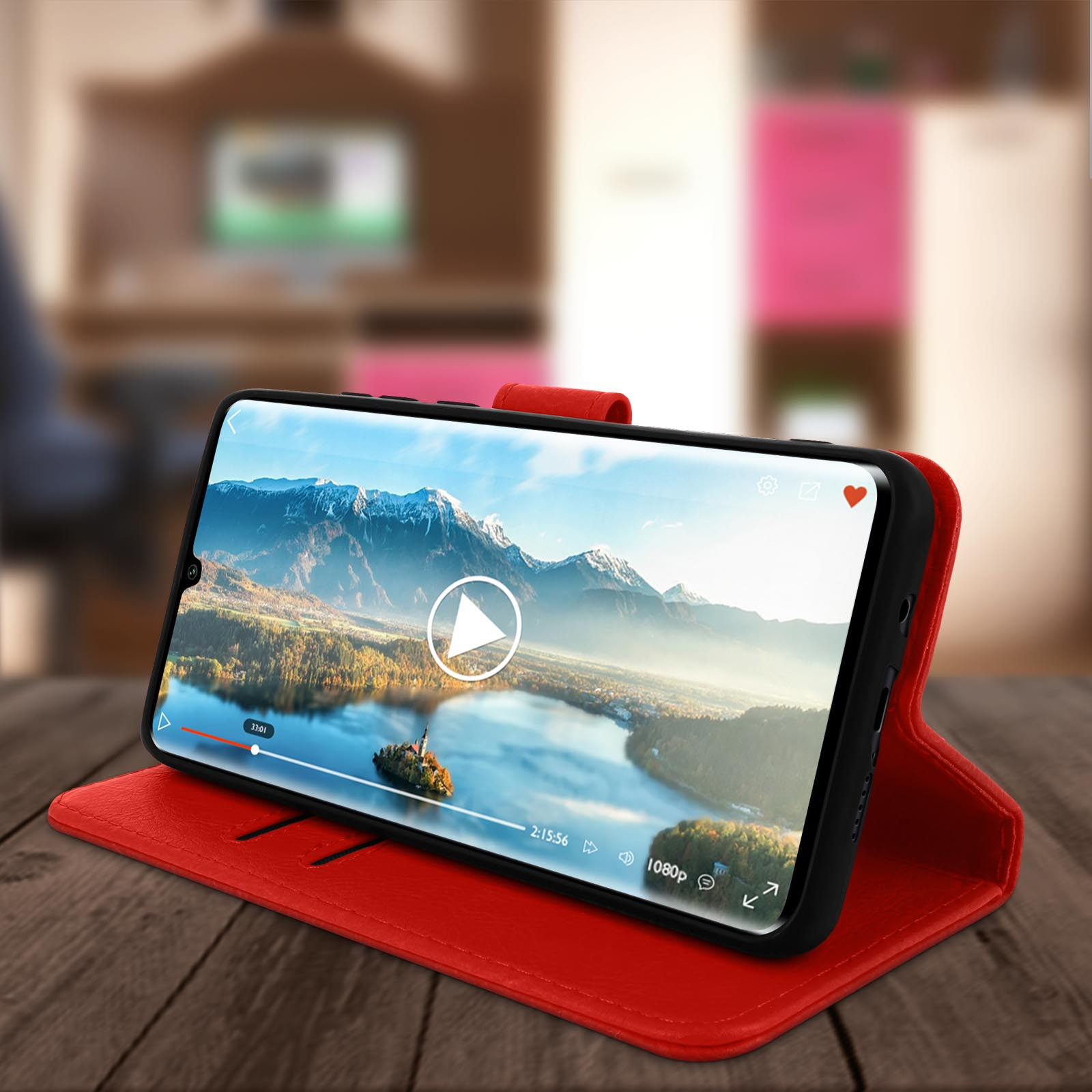 Smartphone in una custodia rossa, in riproduzione di un video. Tavolo di legno e sfondo sfocato.