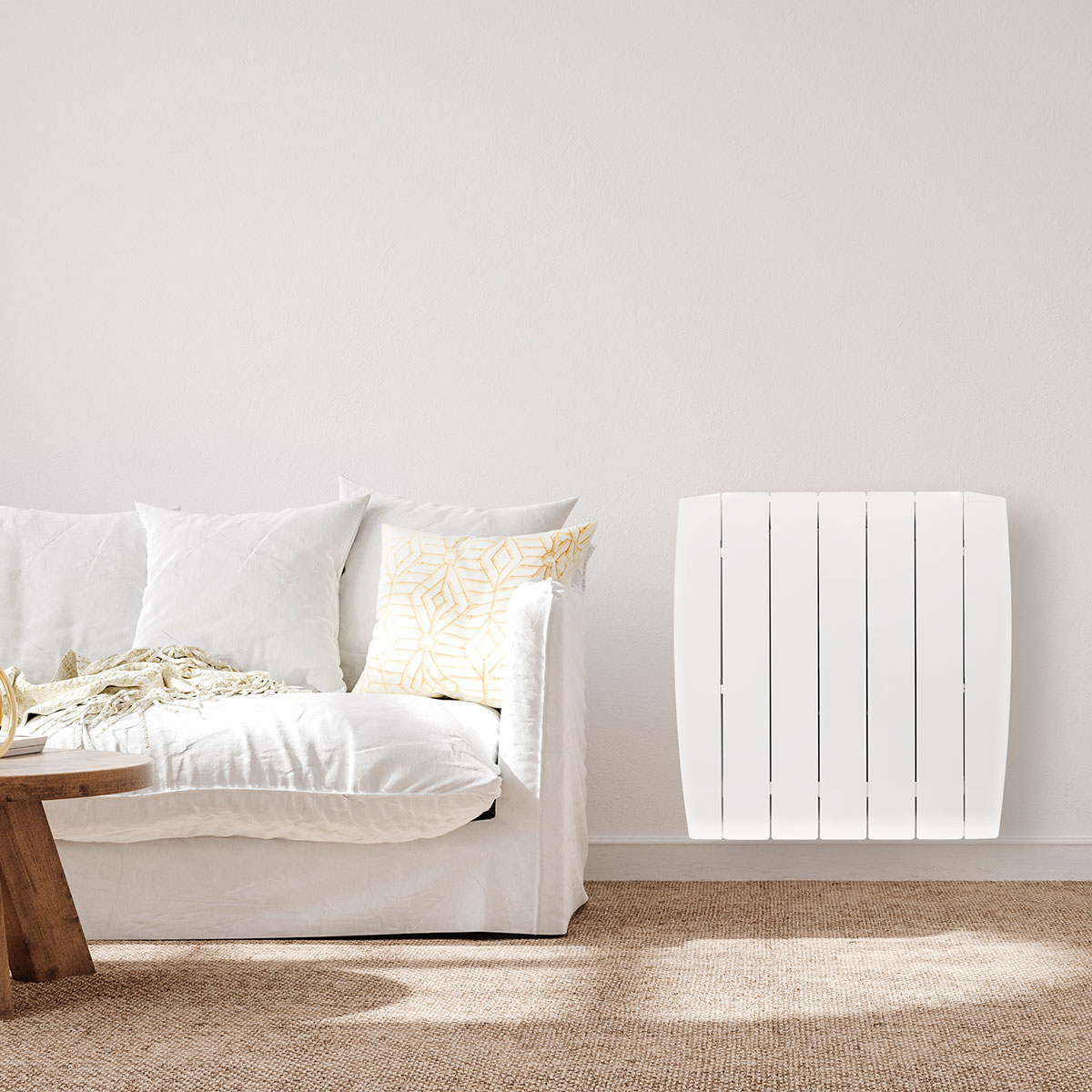 Una pared blanca con un sofá blanco y un radiador blanco. Mesa de madera y alfombra completan la escena.