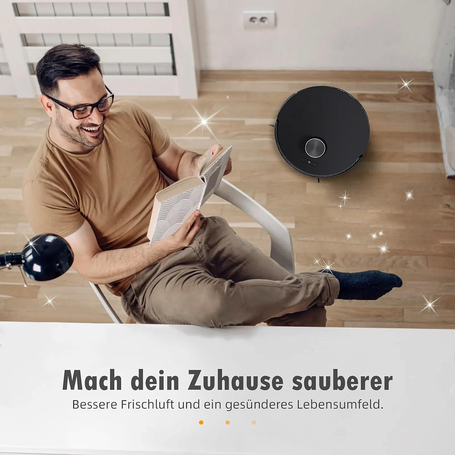 Mężczyzna czyta książkę, uśmiechając się, podczas gdy robot sprząta podłogę.