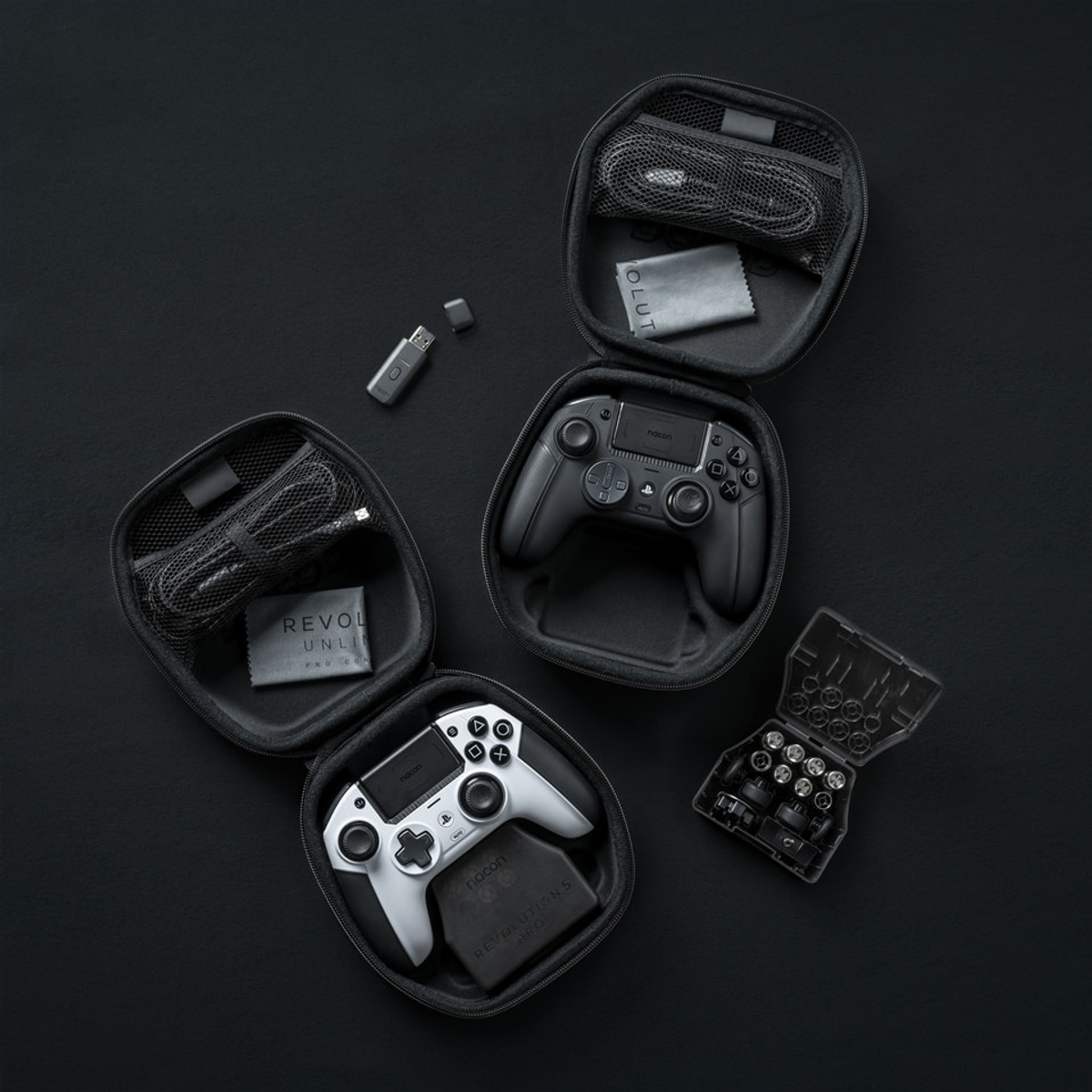 Gaming-Zubehör, darunter Controller, Kabel und ein Schraubendreher-Set, in schwarzen Hüllen auf schwarzer Oberfläche.