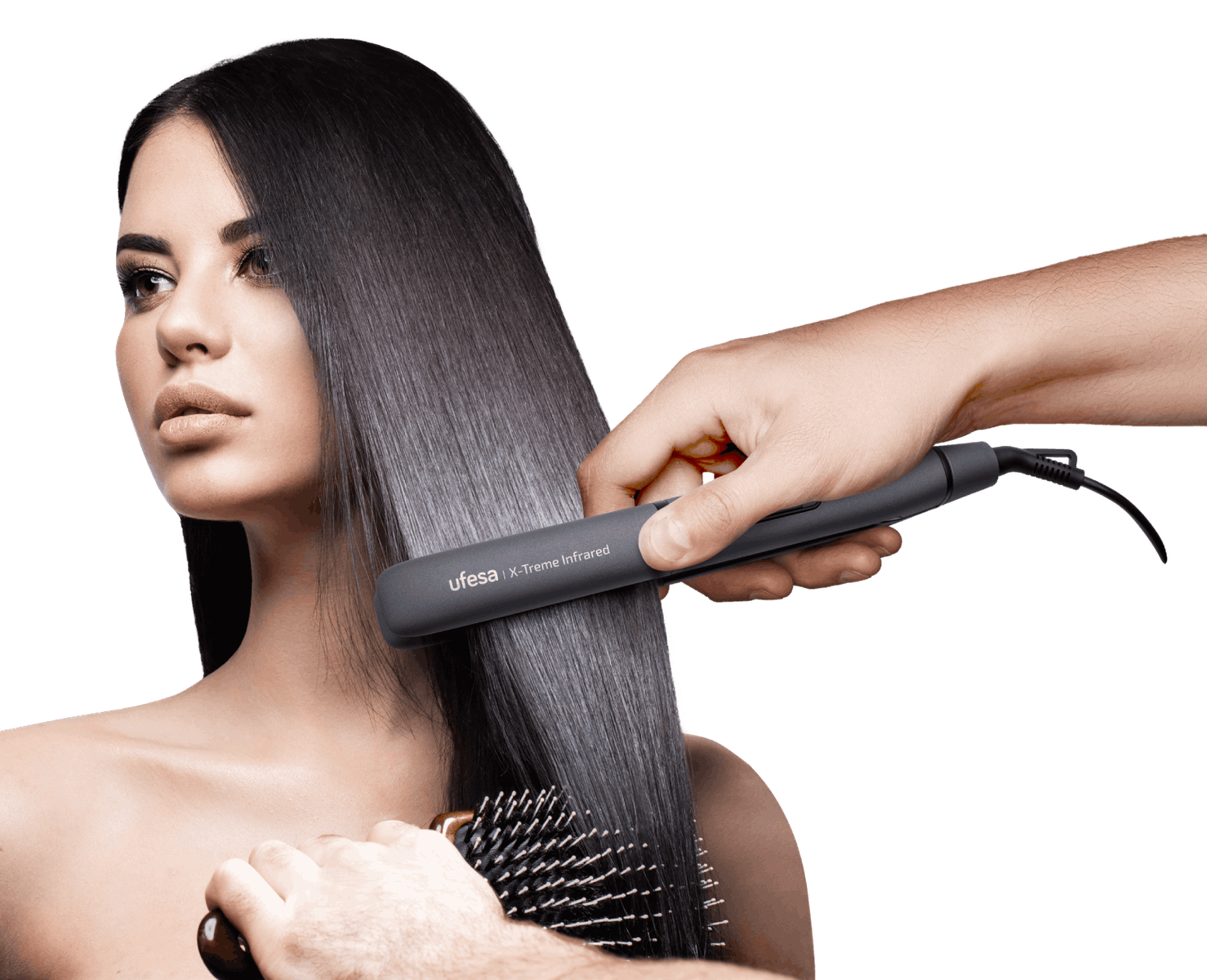 Włosy kobiety są prostowane prostownicą. Osoba trzyma prostownicę i szczotkuje włosy.