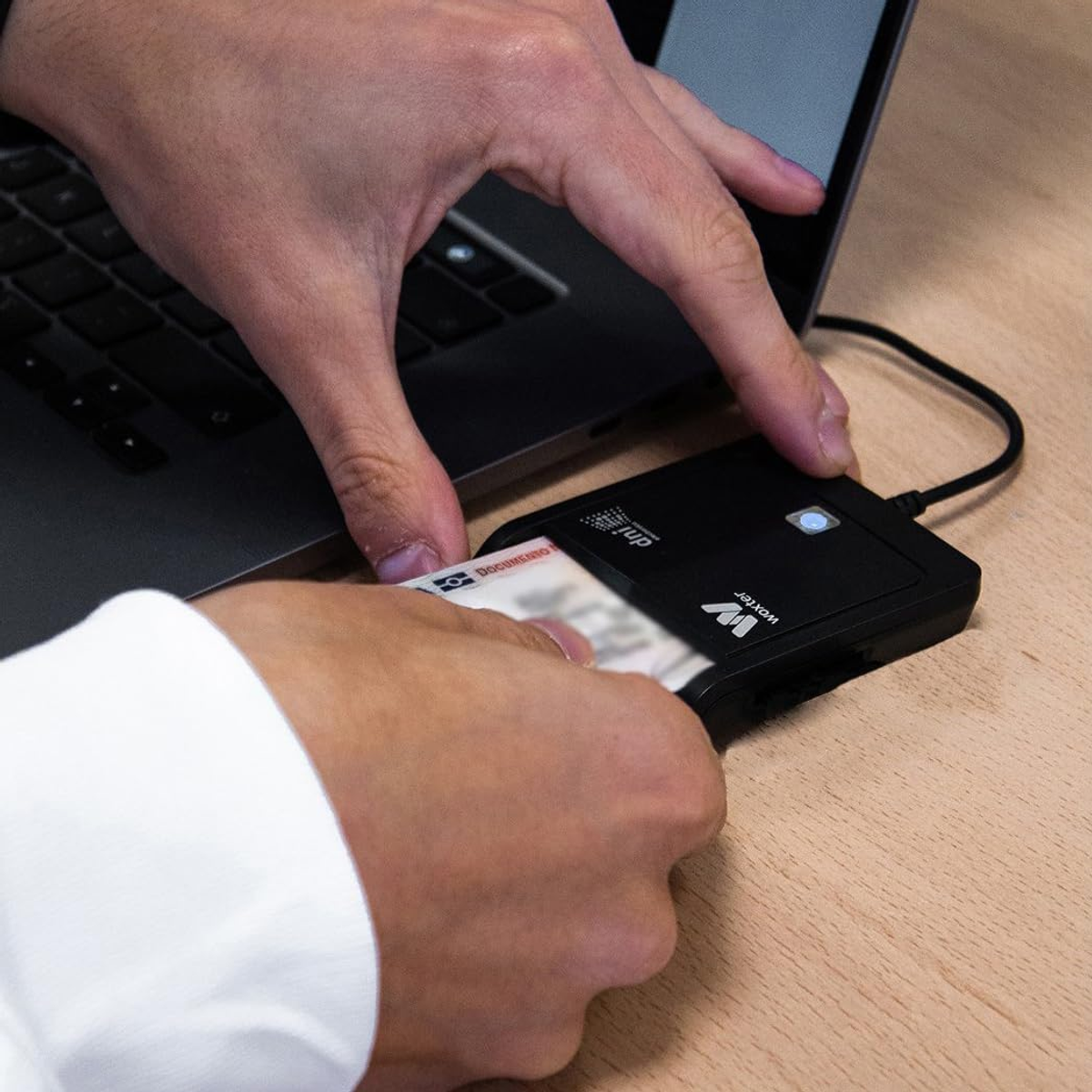 Una persona inserisce una carta in un lettore di carte nero collegato a un laptop.