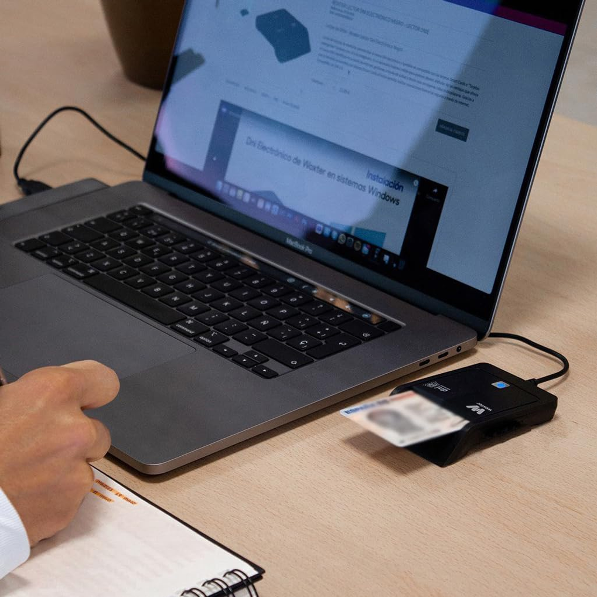 Una persona usa un laptop e un lettore di schede. Lo schermo mostra una pagina web.