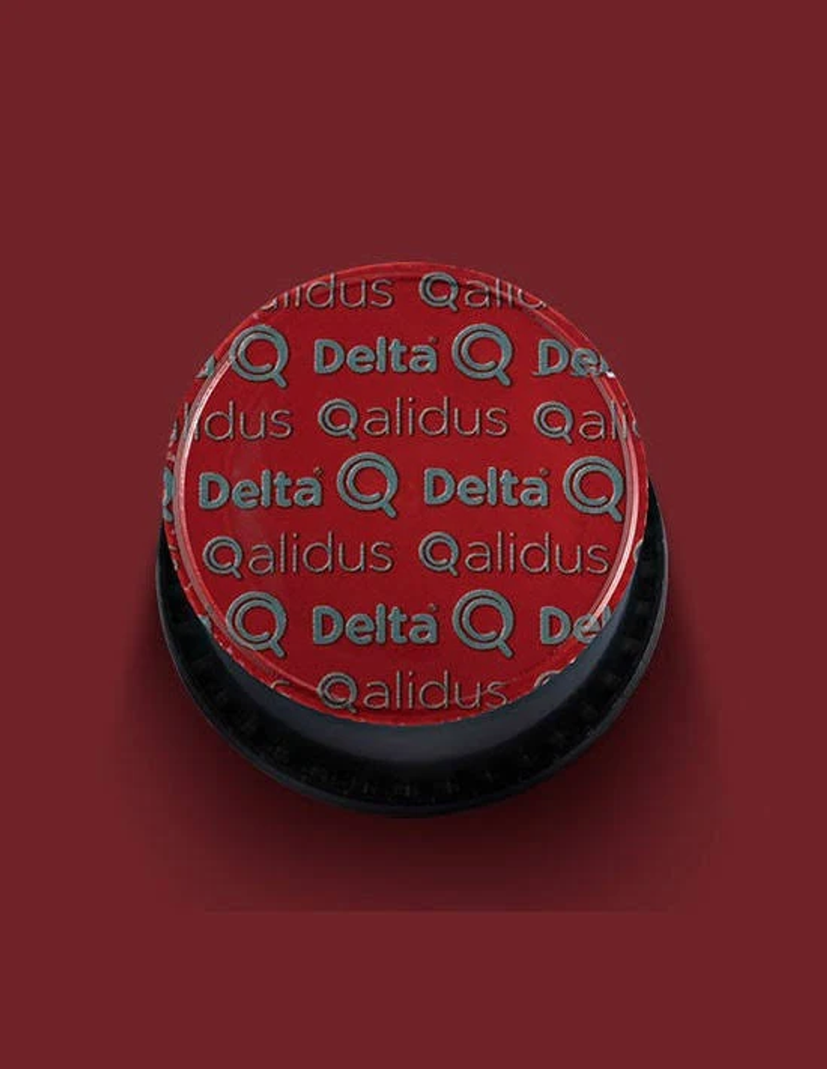 Capsula di caffè rossa con logo e testo argentati, su sfondo scuro.