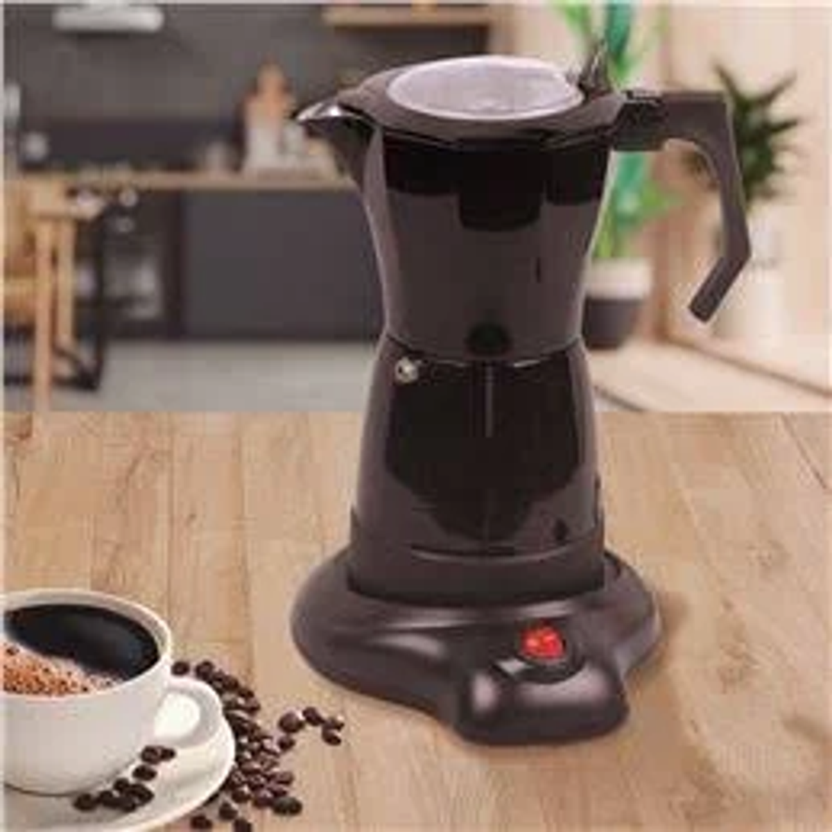 Cafetera eléctrica negra con una taza de café y granos de café sobre una mesa de madera.