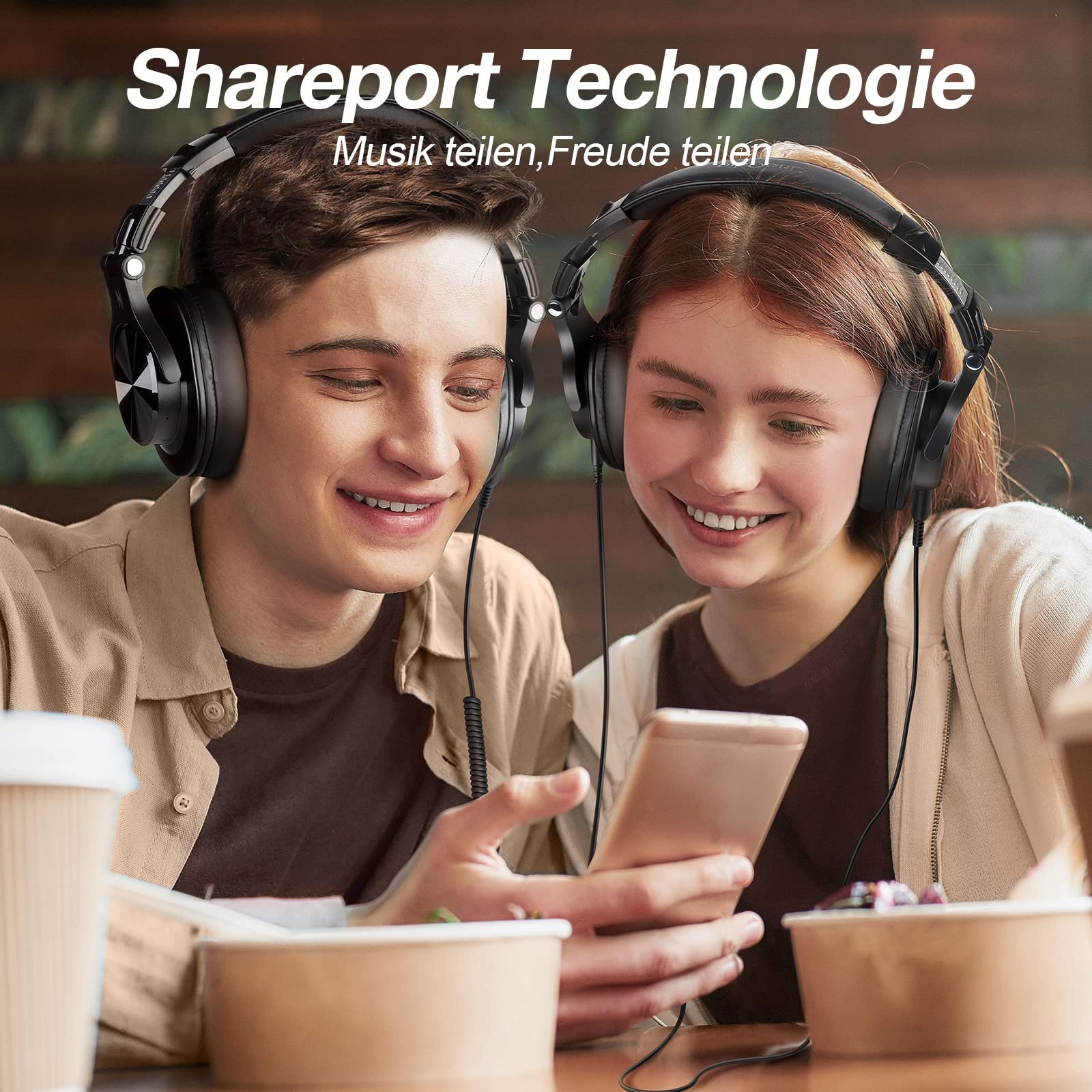 Zwei Personen mit Kopfhörern hören Musik von einem Smartphone und lächeln.