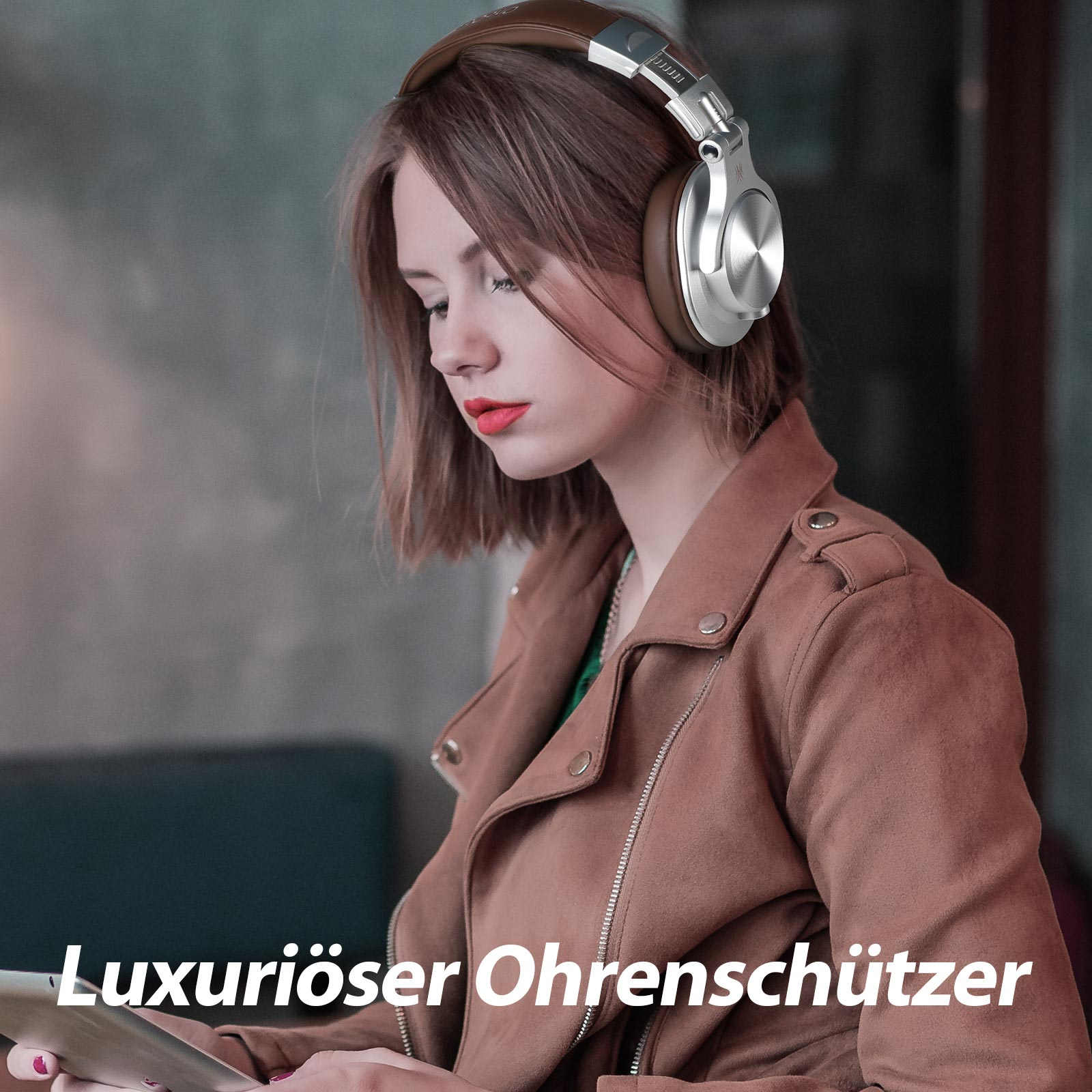 Eine Frau mit braunen Kopfhörern, die in einem Café sitzt und etwas betrachtet.
