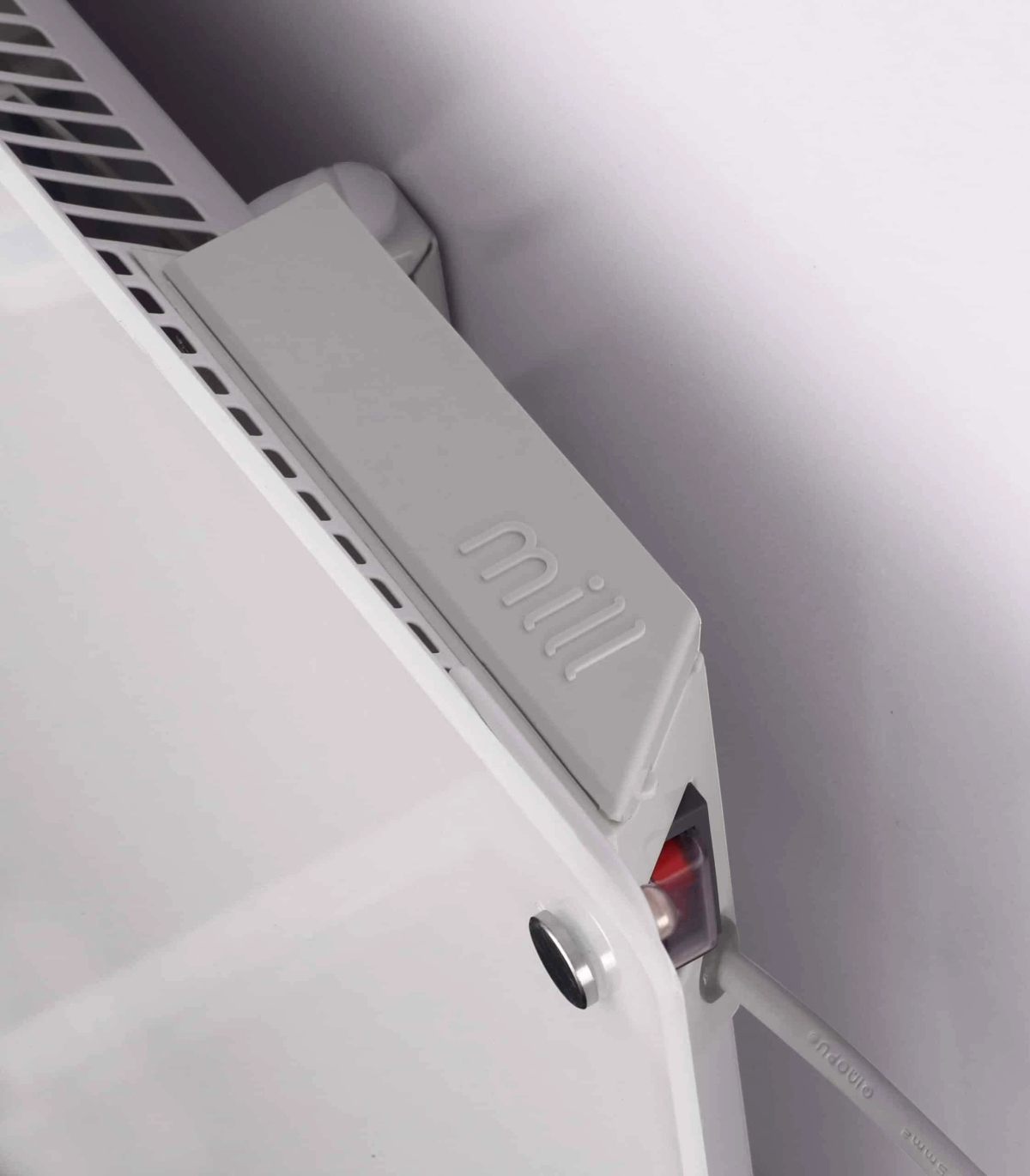 Un calefactor blanco montado en una pared. El panel tiene el logo 'mill' y un botón rojo.