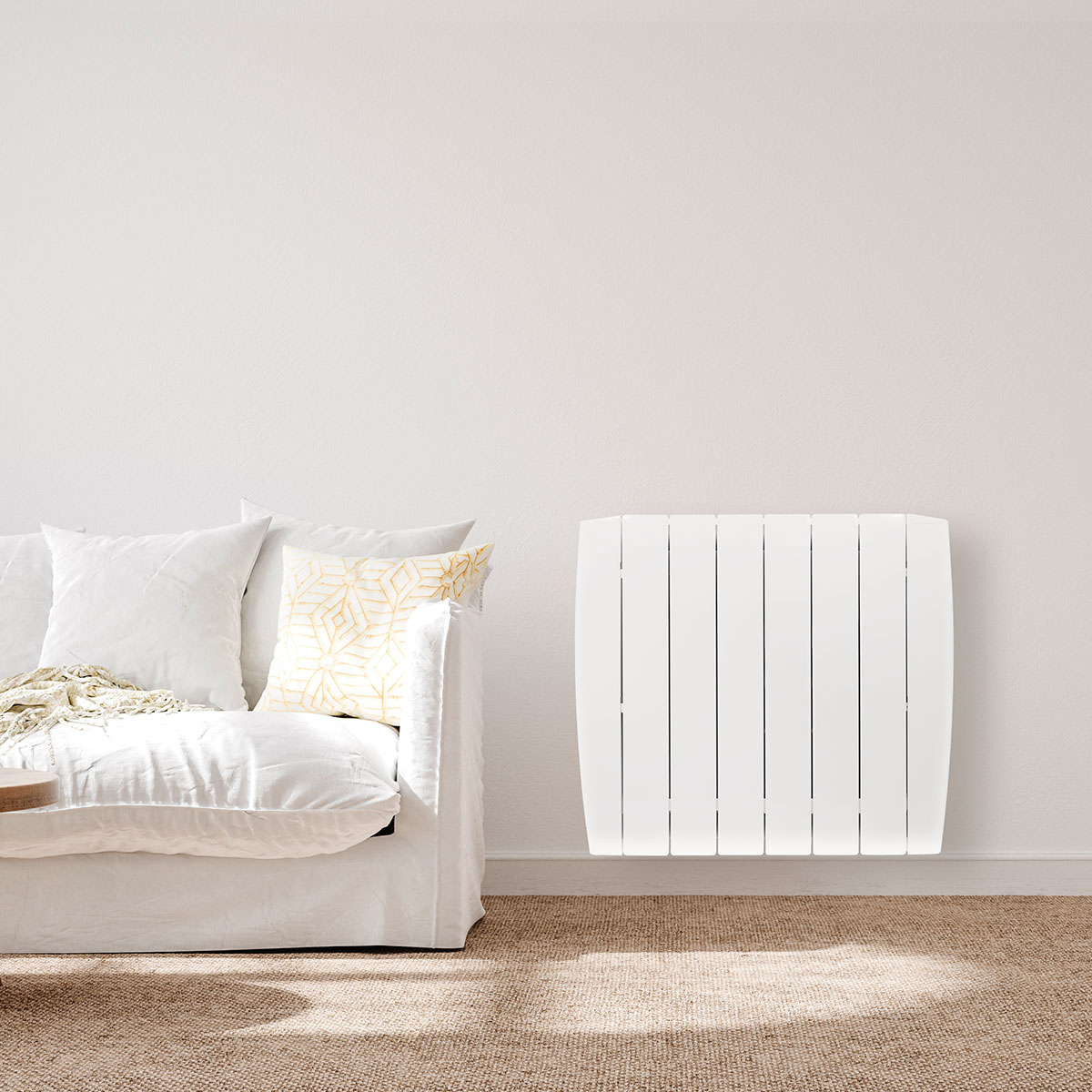Un calefactor eléctrico blanco en una pared junto a un sofá blanco con almohadas y una alfombra en un suelo de madera.