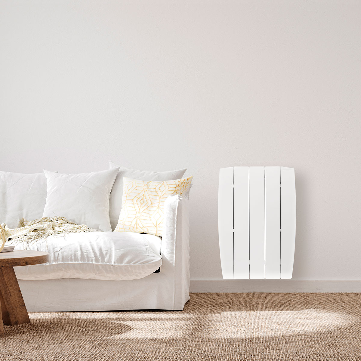 Un calentador eléctrico blanco contra una pared blanca, junto a un sofá blanco y una mesa de madera.