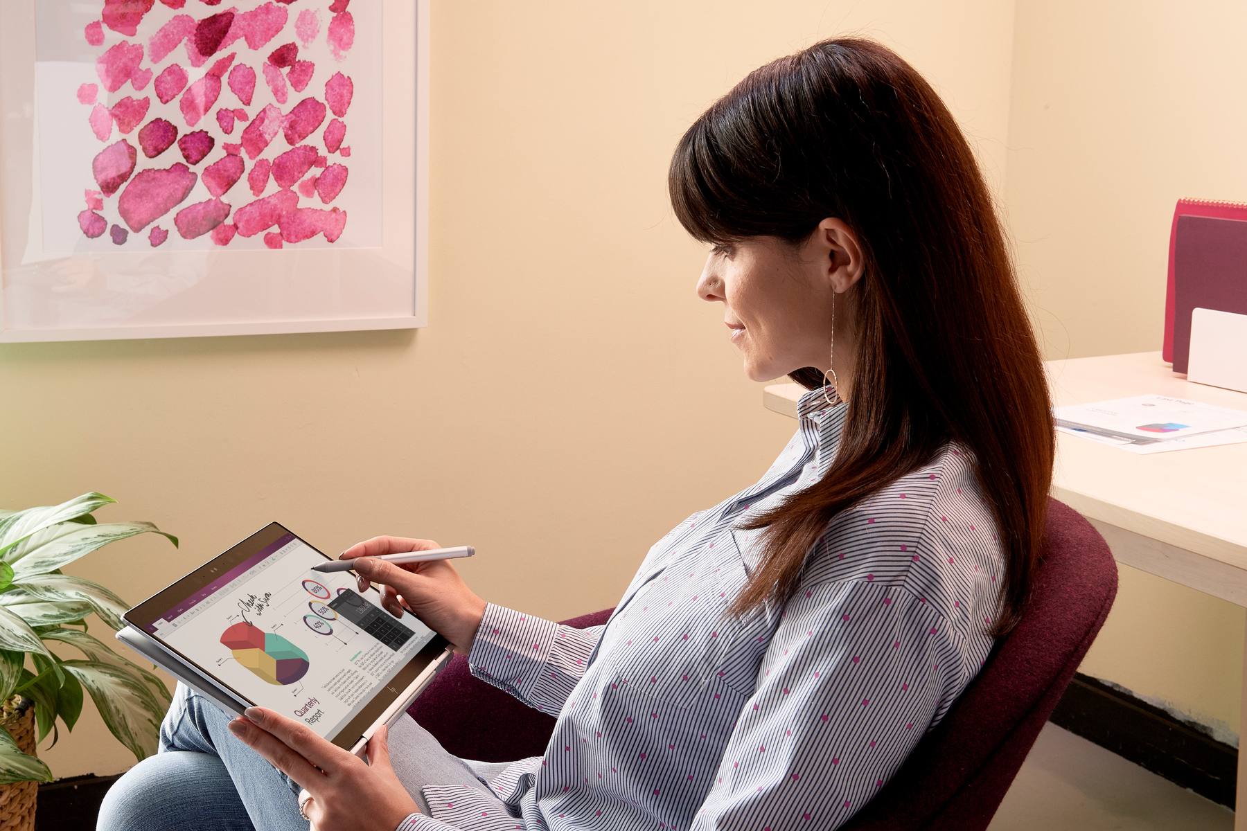 Kobieta siedzi i używa tabletu. Patrzy na wykres na ekranie, trzymając rysik.