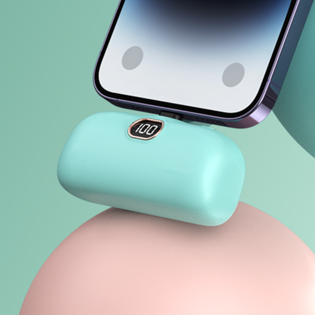 Ein Telefon, das an einer kleinen, türkis farbenen Powerbank mit Digitalanzeige geladen wird.
