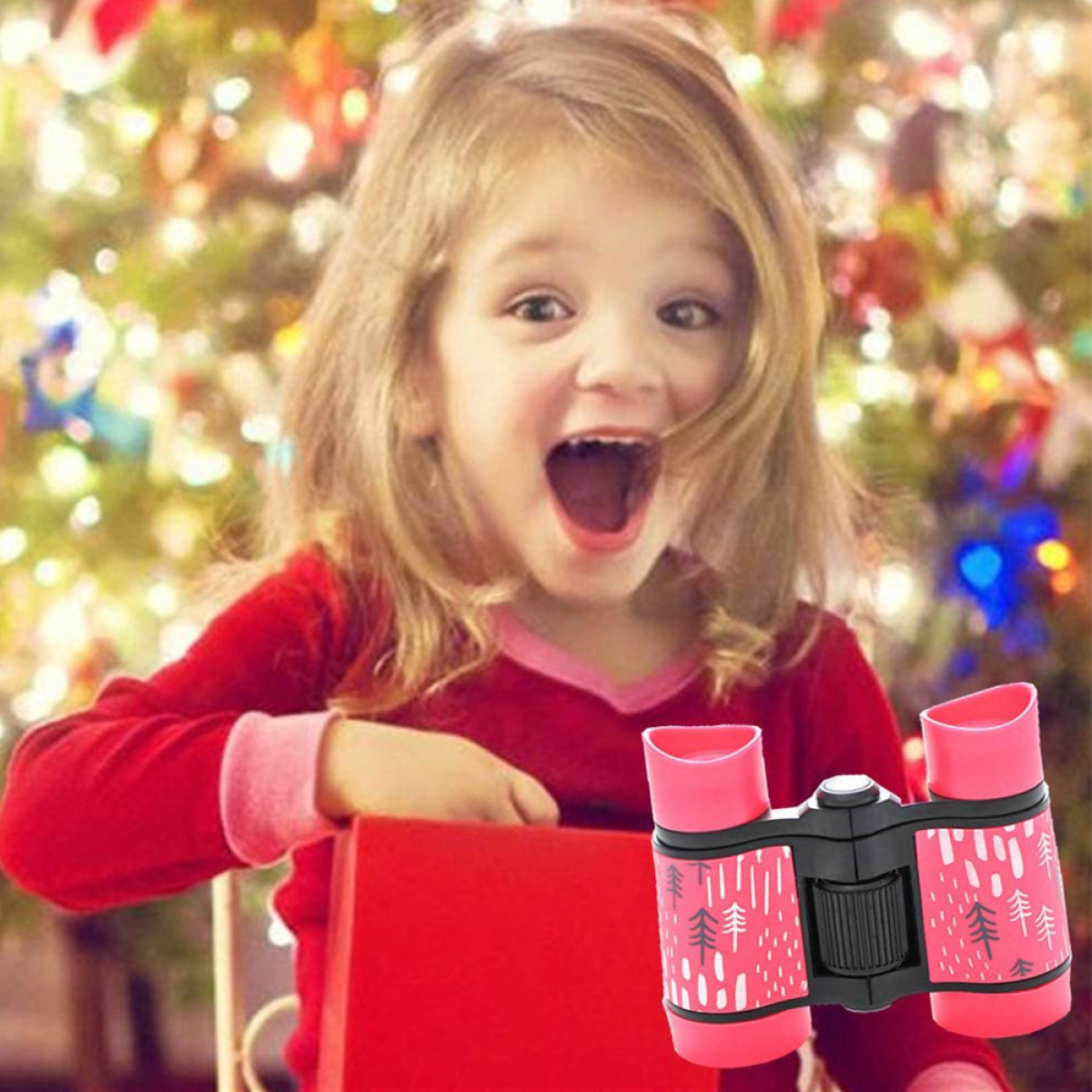 Ein Mädchen mit offenem Mund hält eine rote Box mit roten und pinkfarbenen Ferngläsern; Weihnachts-Hintergrund.