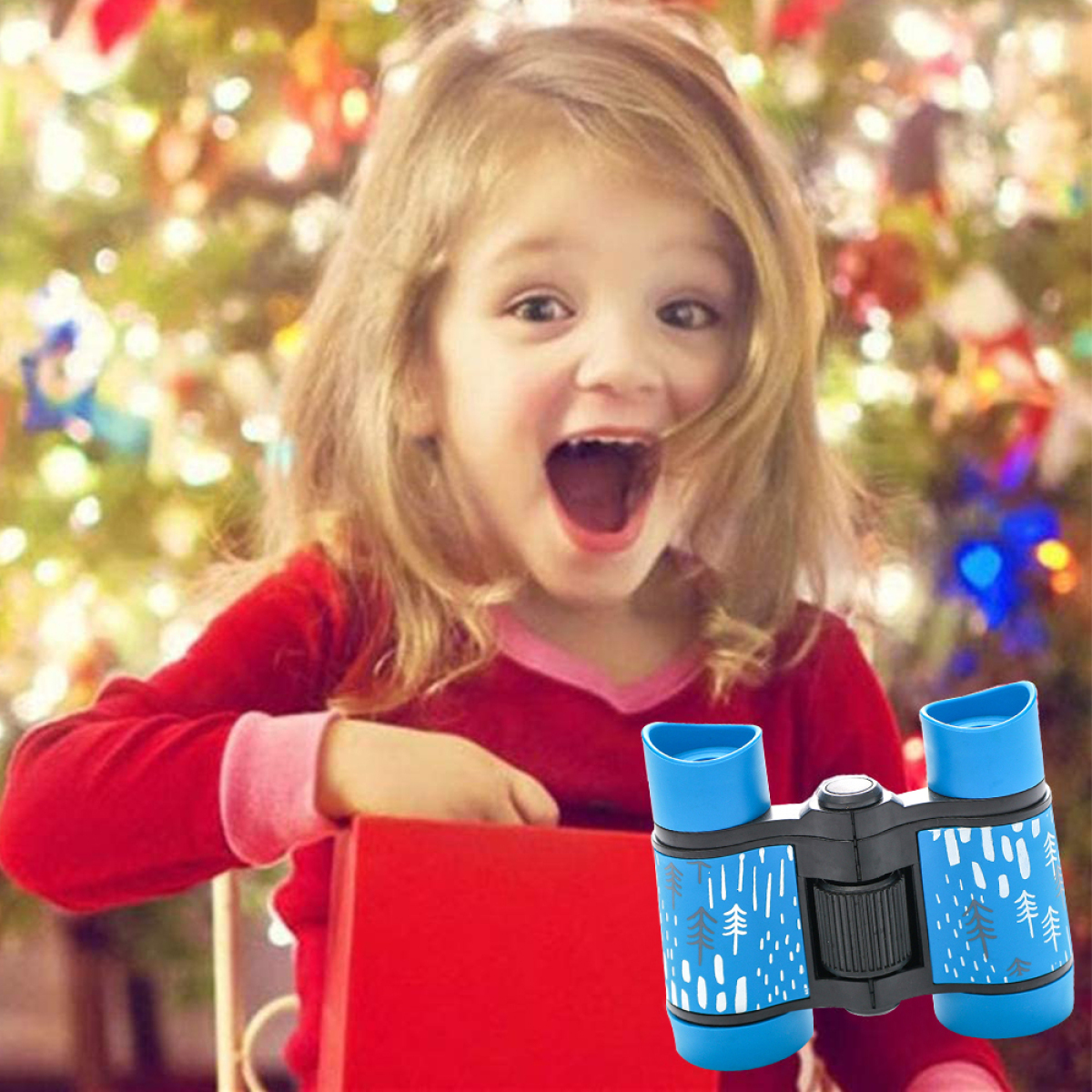 Ein junges Mädchen mit offenem Mund und rotem Hemd, schaut auf ein blaues Fernglas. Ein Weihnachtsbaum im Hintergrund.