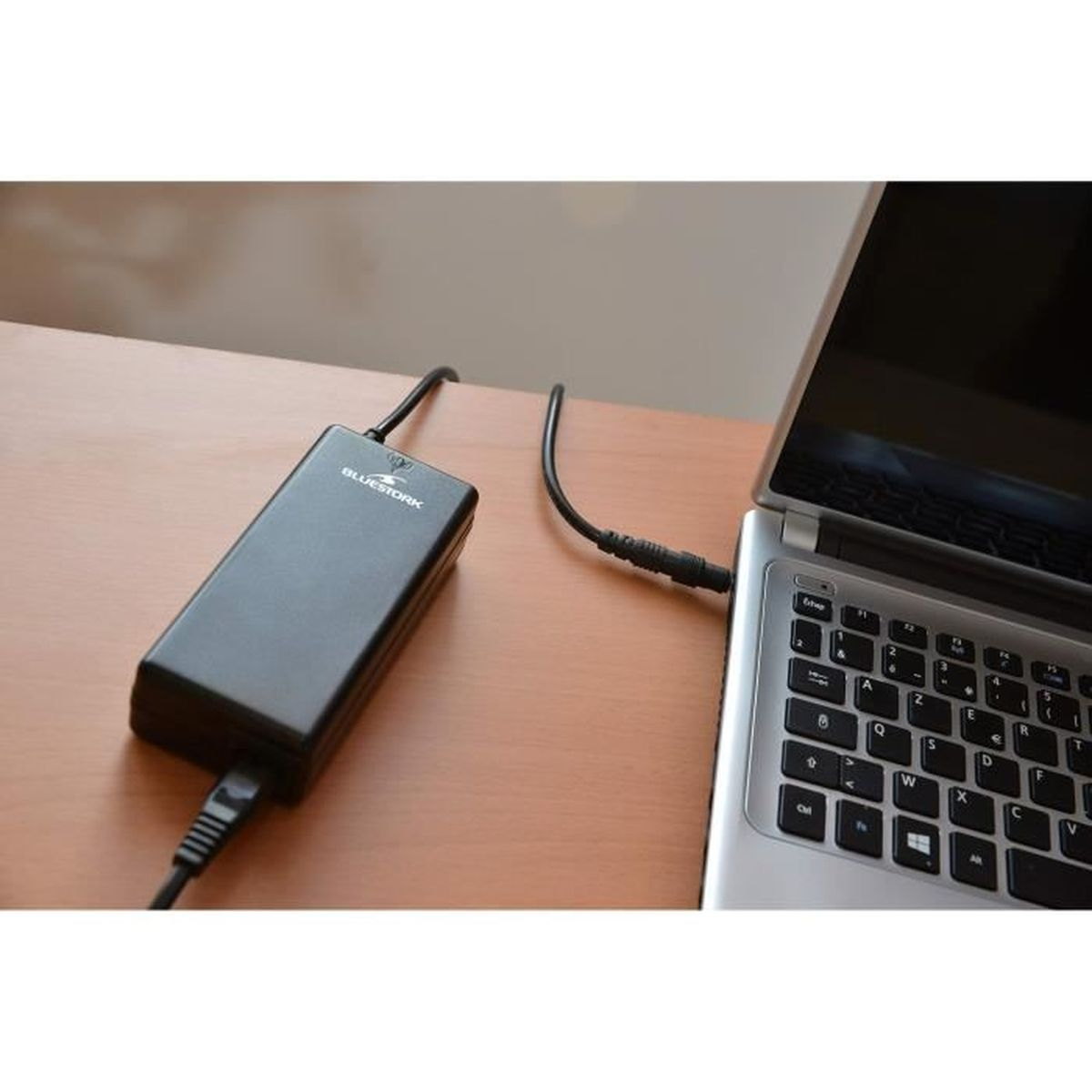 Schwarzes Ladegerät, das mit einem Laptop verbunden ist. Brauner Schreibtisch.