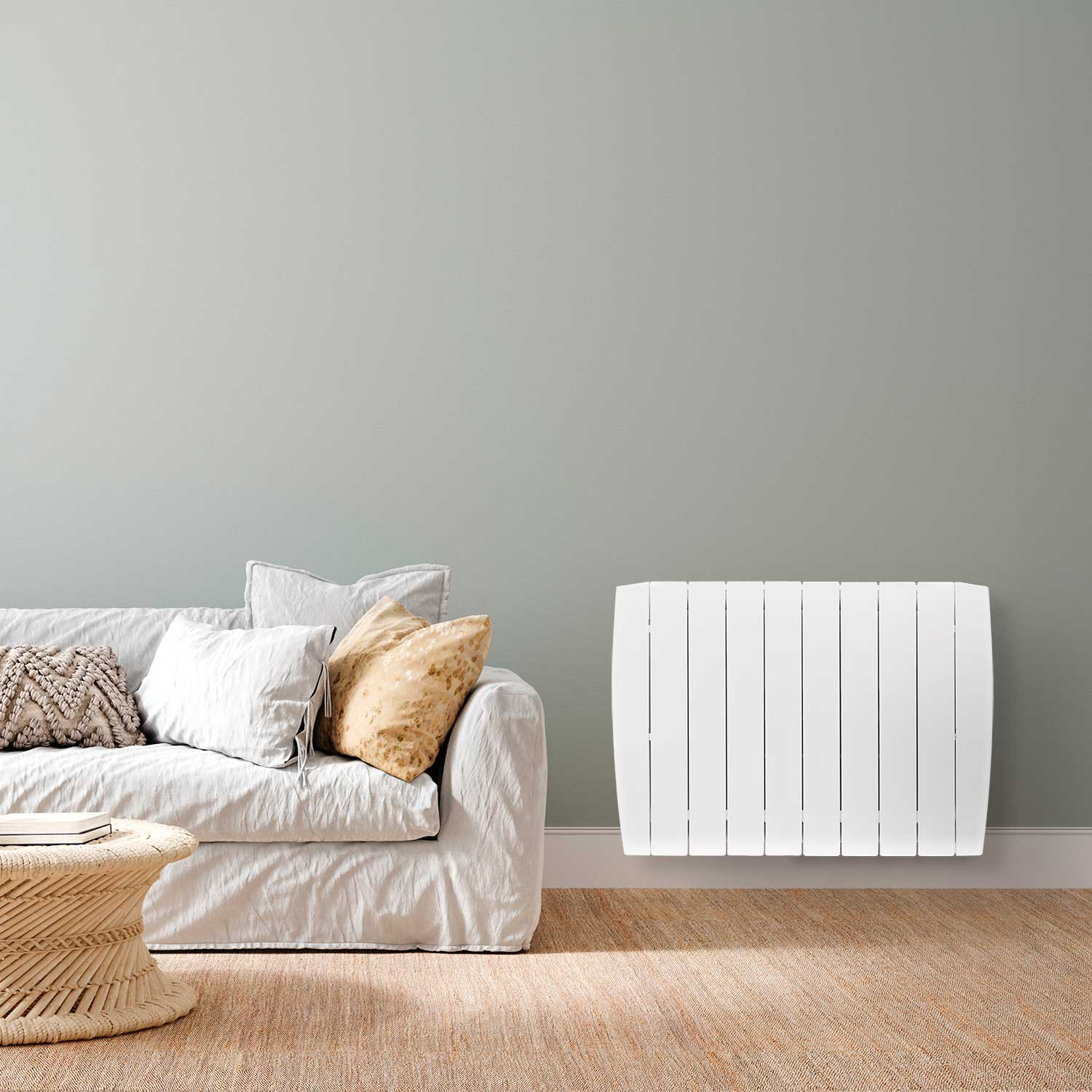 Un radiador blanco montado en una pared gris, cerca de un sofá blanco.