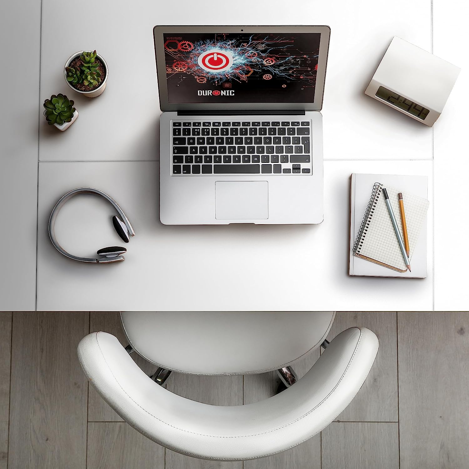 Laptop mit Power-Button-Bildschirm, Kopfhörer, Notizbuch und Pflanzen auf einem weißen Schreibtisch. Stuhl ist unten.