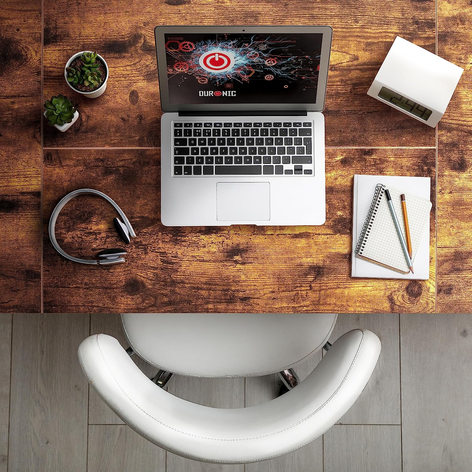 Laptop auf einem Holzschreibtisch mit Kopfhörern, Notizblock, Sukkulenten und einem Stuhl.