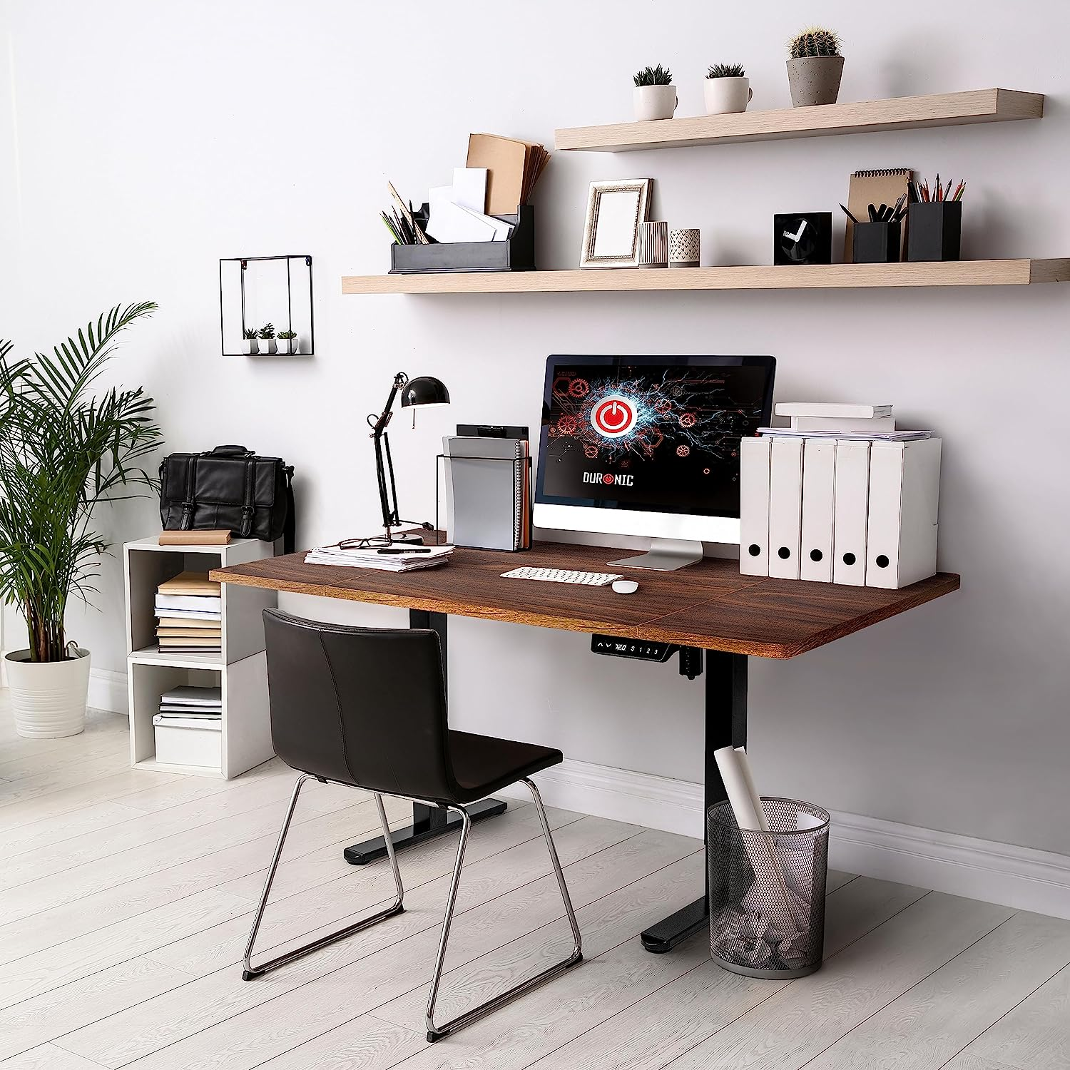 Bürotisch mit Computer, Lampe und anderen Gegenständen. Weißer Wandhintergrund.