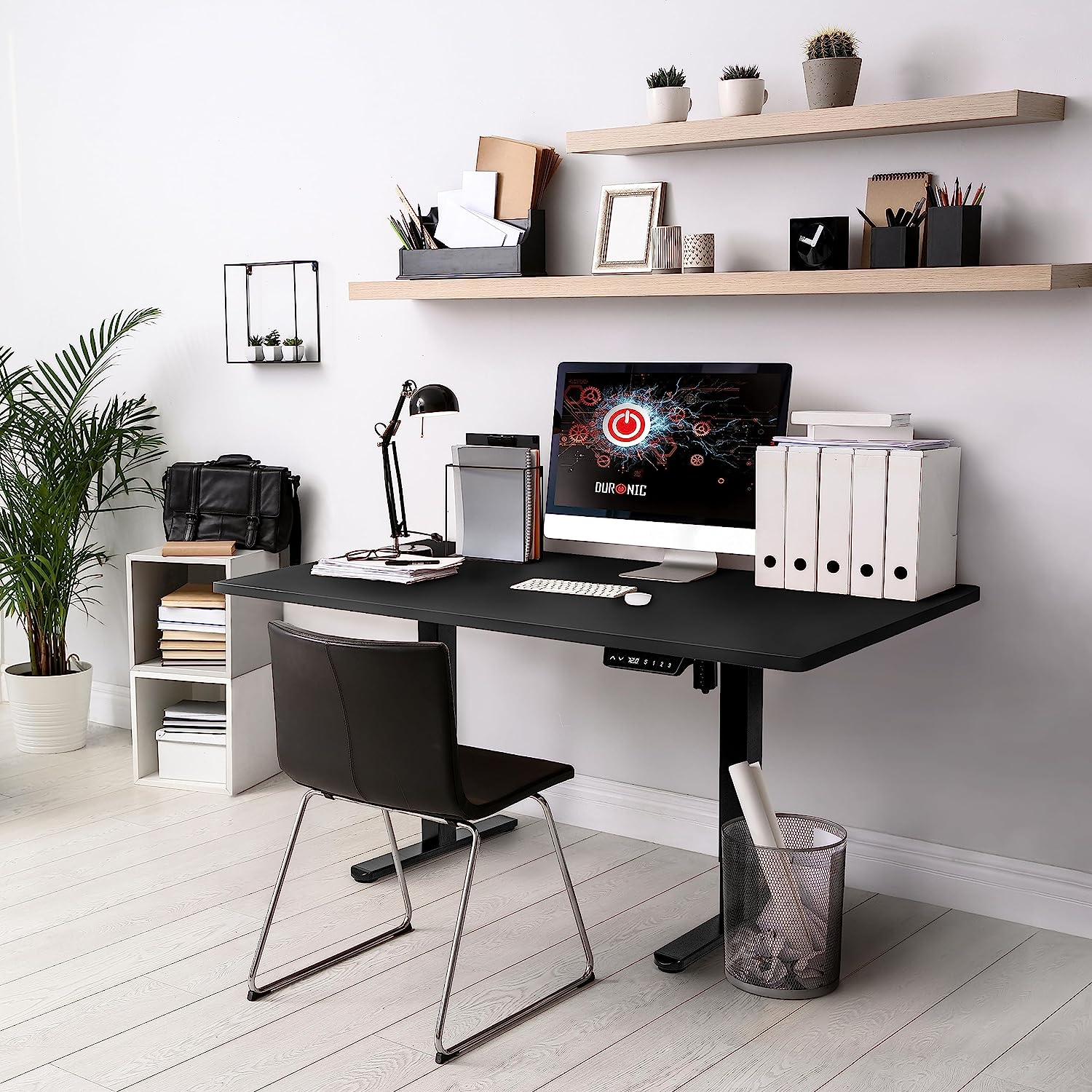 Moderner Bürotisch mit Computer, Stuhl und Zubehör vor weißer Wand, Holzregale.