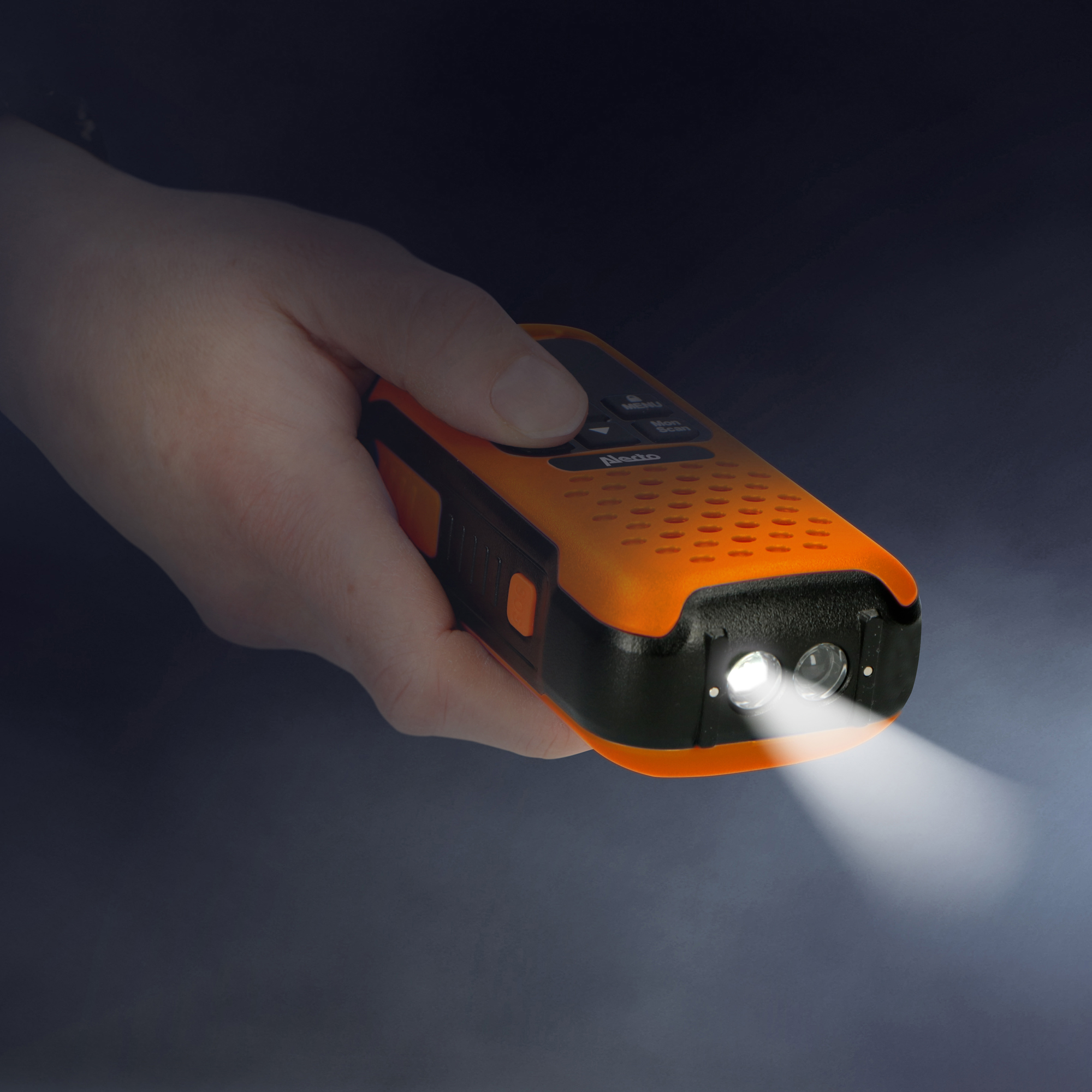 Dłoń trzyma pomarańczowo-czarną latarkę, świeci światło.