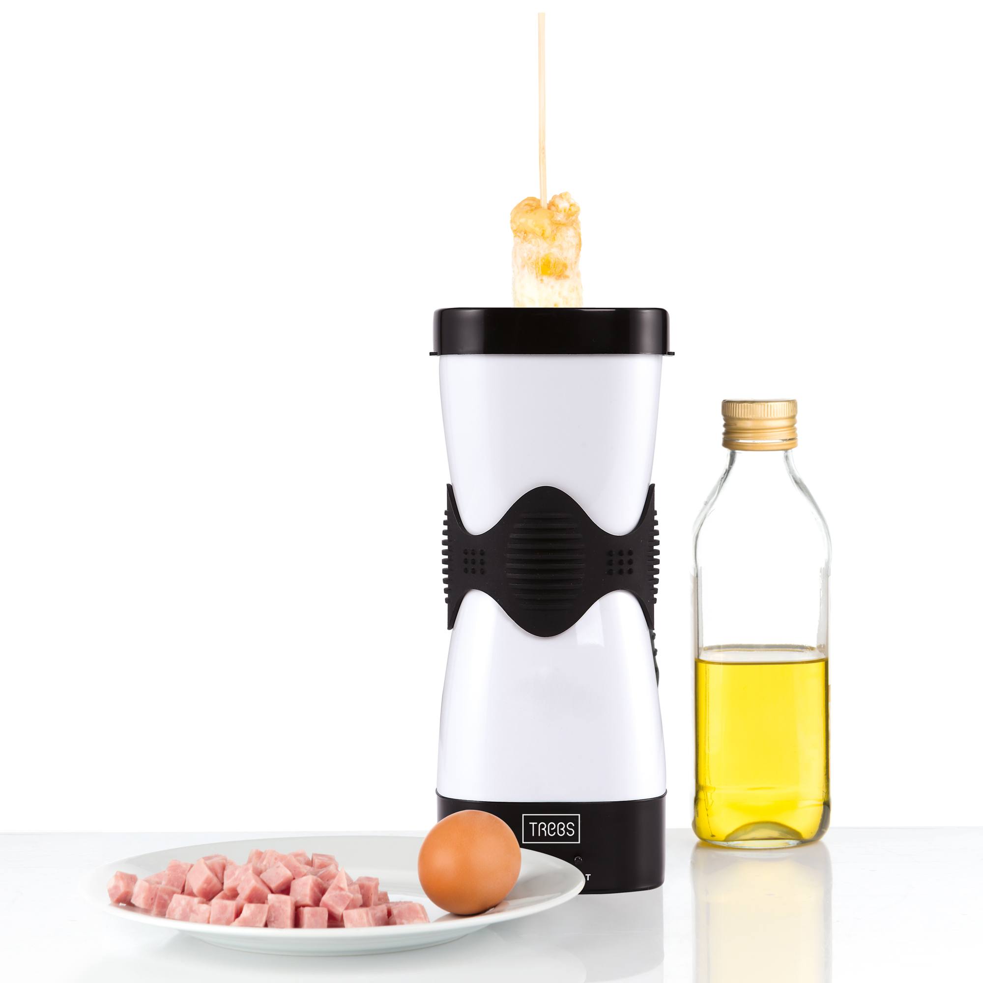 Una macchina per uova con uovo, prosciutto e bottiglia di olio su una superficie bianca. Lo sfondo è bianco.