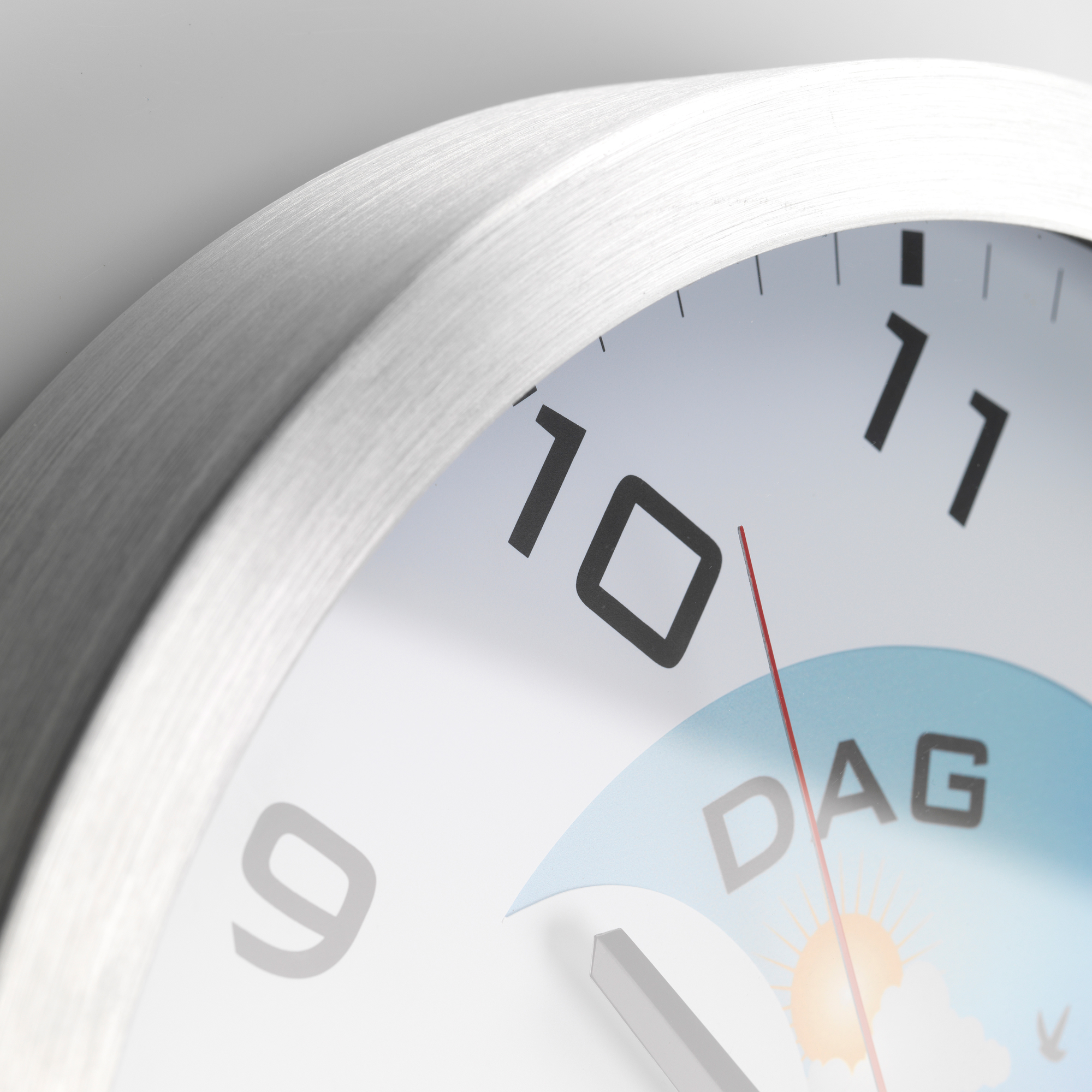 Nahaufnahme eines Zifferblatts. Die Uhr zeigt die Zahl 10 und das Wort DAG.