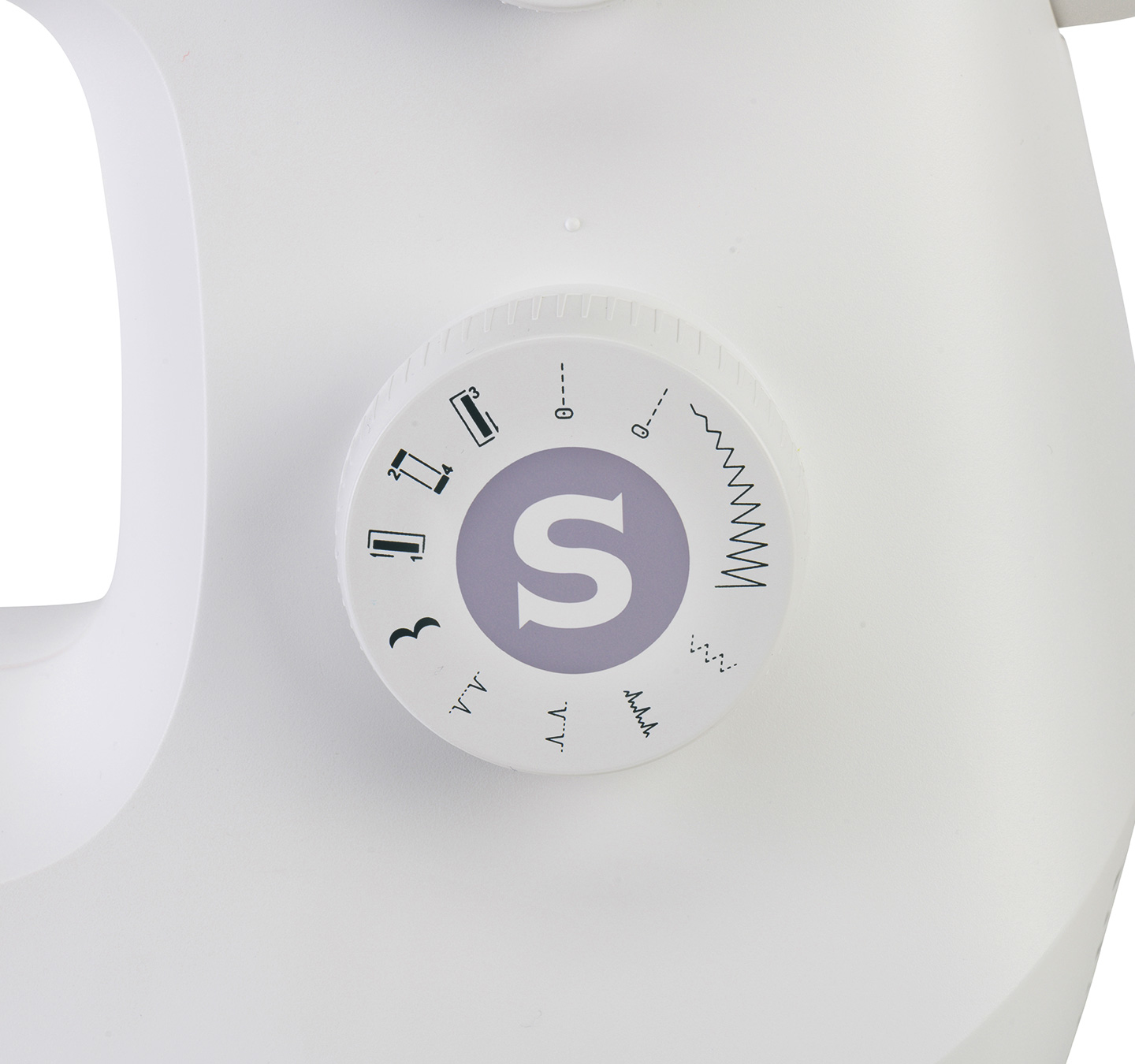 Zbliżenie pokrętła maszyny do szycia. Pokazuje wybory ściegów i dużą literę 'S'.