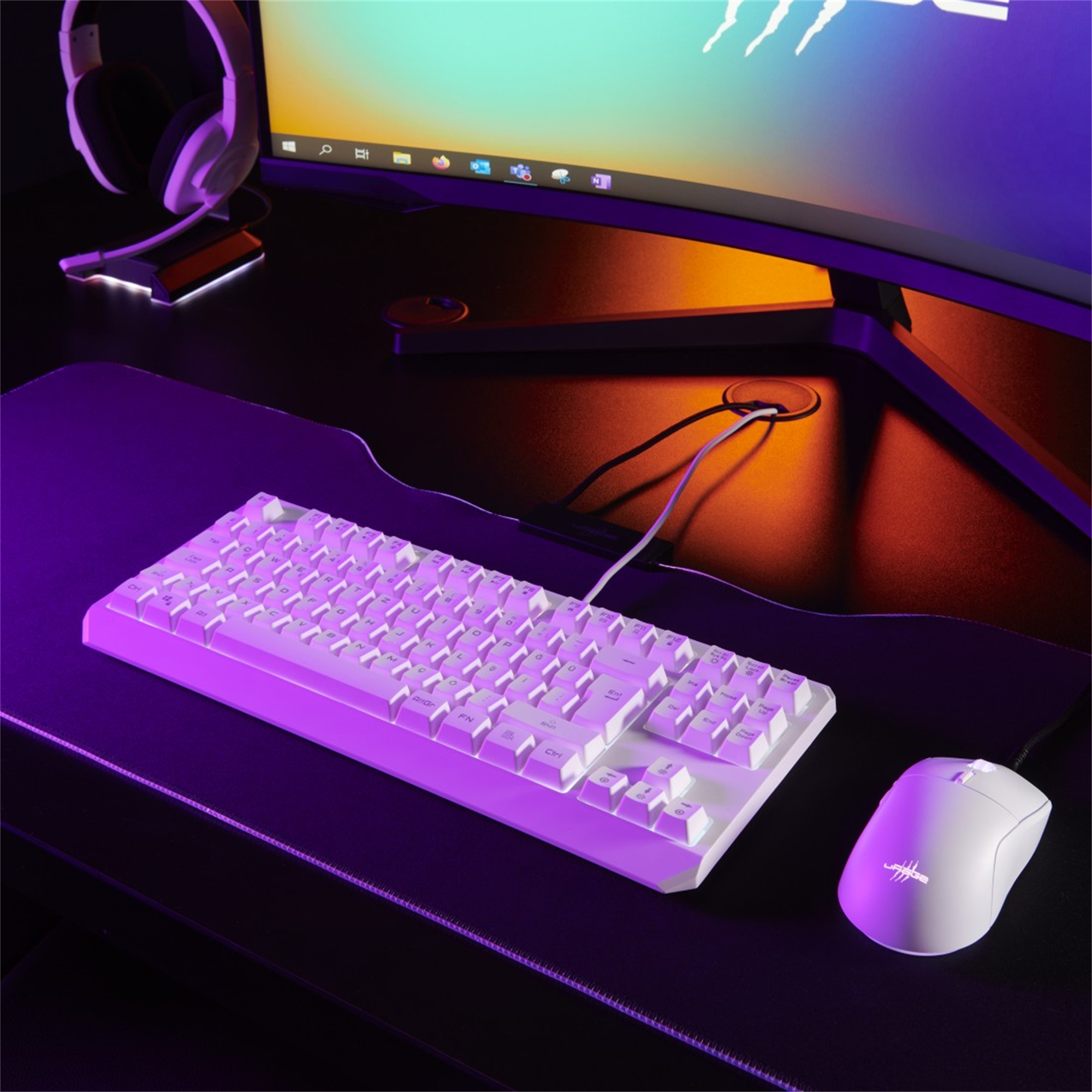Weißes Tastatur- und Maus-Setup auf einem Schreibtisch, mit einem Monitor, der einen farbenfrohen Hintergrund zeigt.