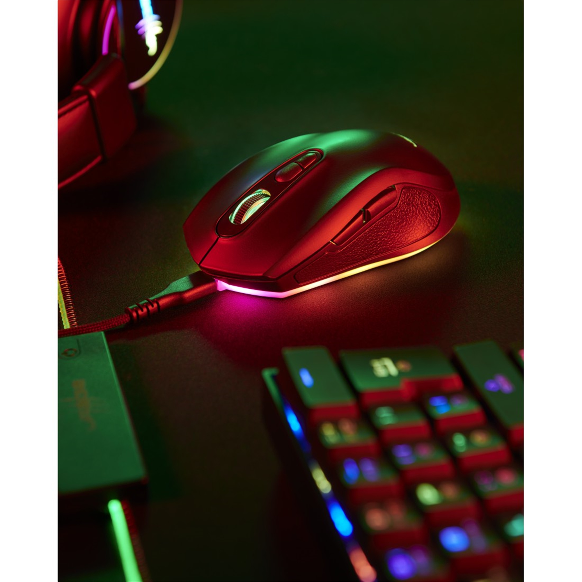 Mouse da gaming nero su una scrivania con illuminazione RGB e tastiera.
