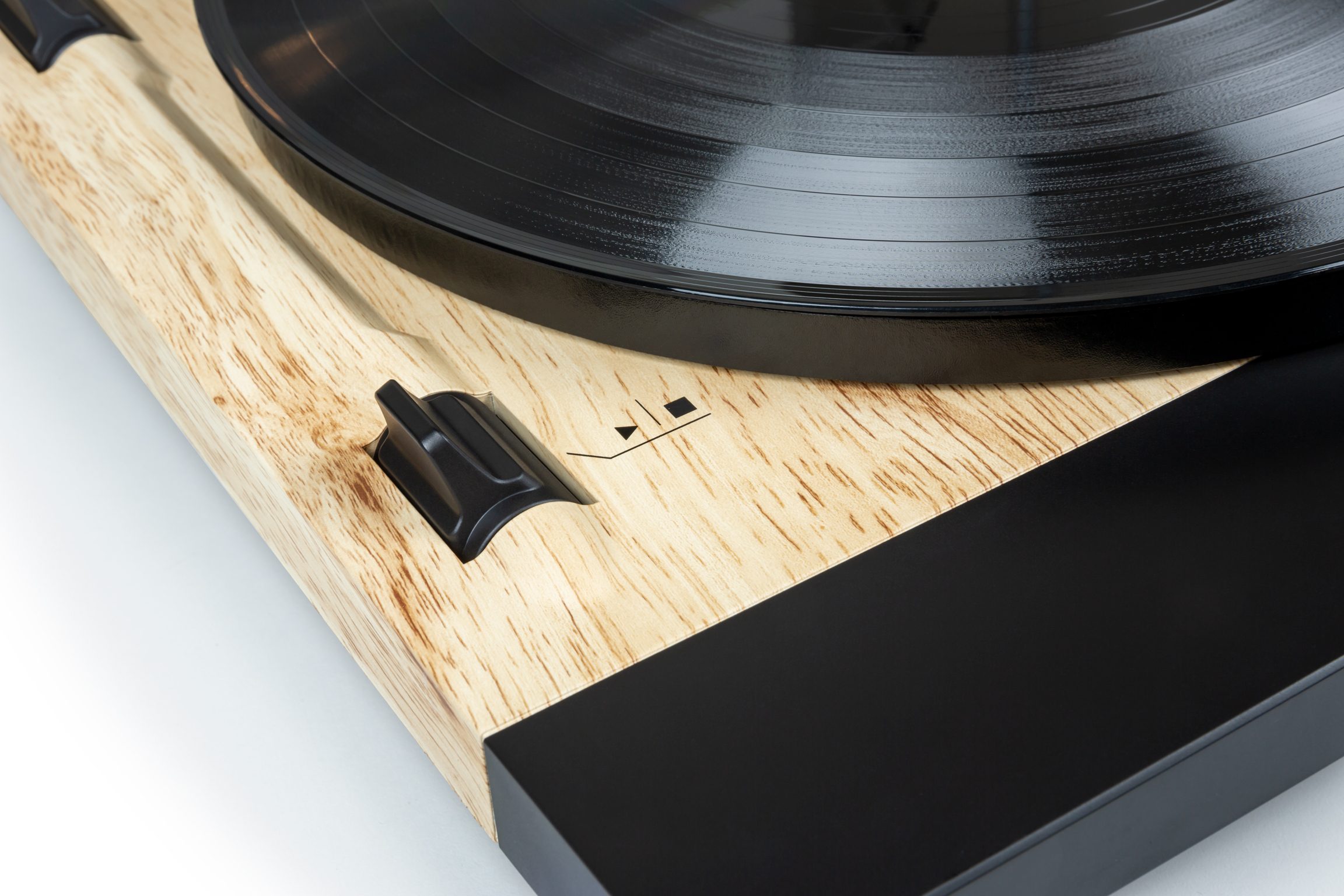 Primer plano de un tocadiscos. El disco es negro. Hay botones de control en el lateral.