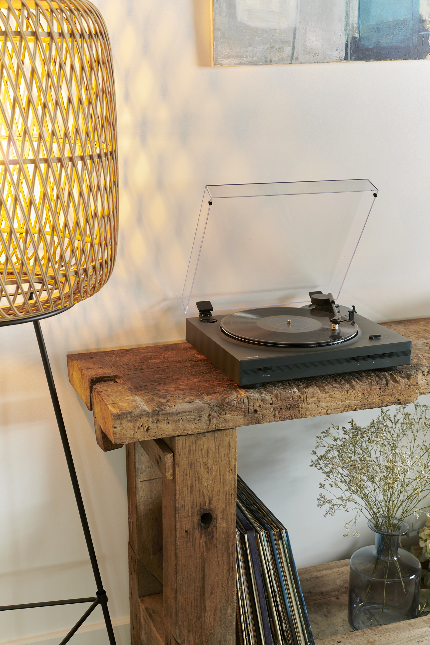 Tocadiscos sobre un banco de madera, con una lámpara y discos.