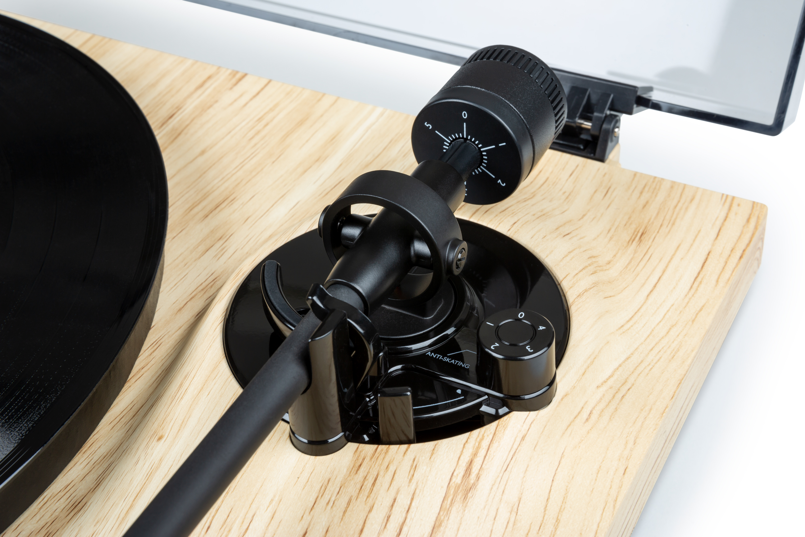 Primer plano de un tocadiscos con brazo negro, disco negro y superficie de madera.