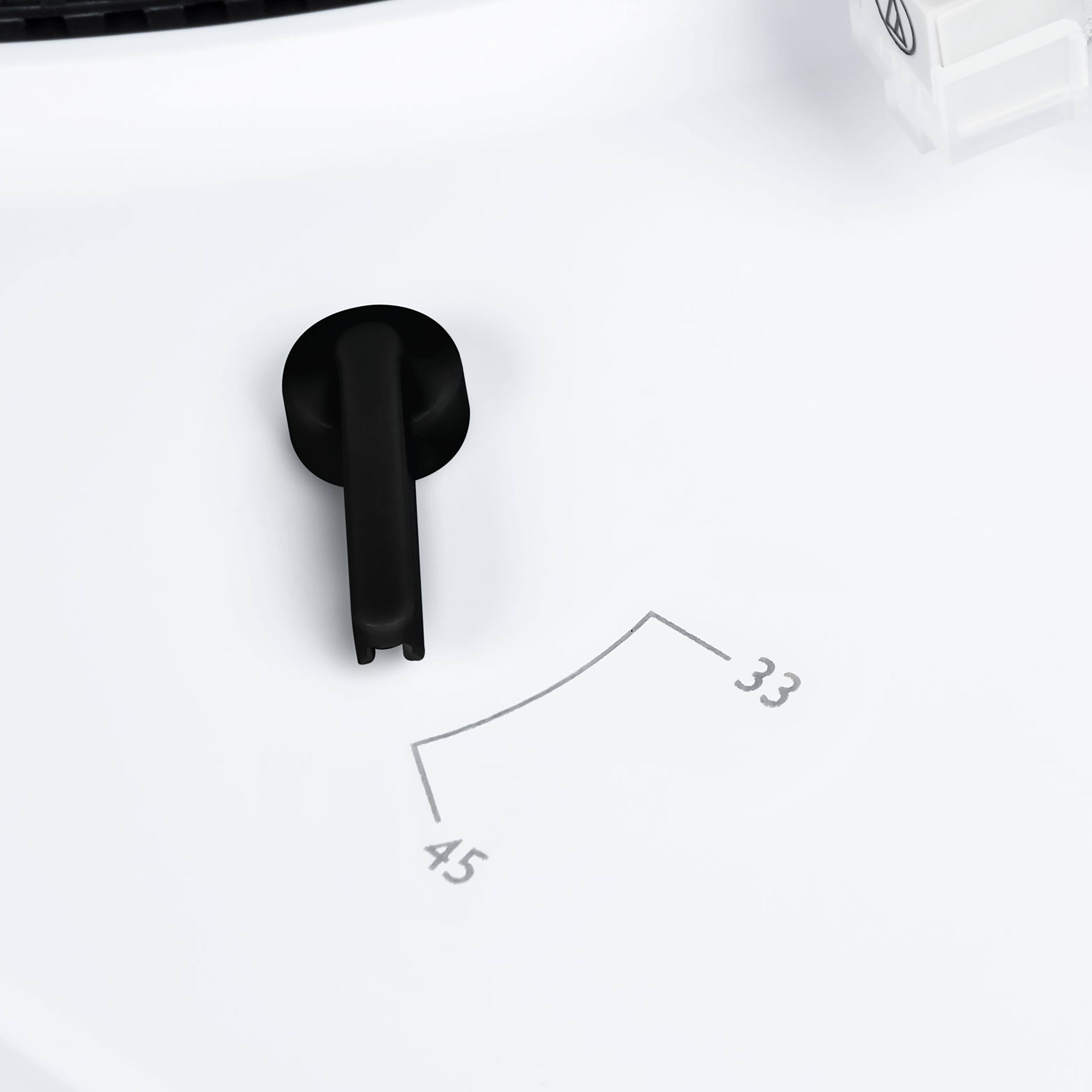 Biały gramofon z czarną dźwignią i tarczą wyświetlającą 33 i 45. Tło jest białe.