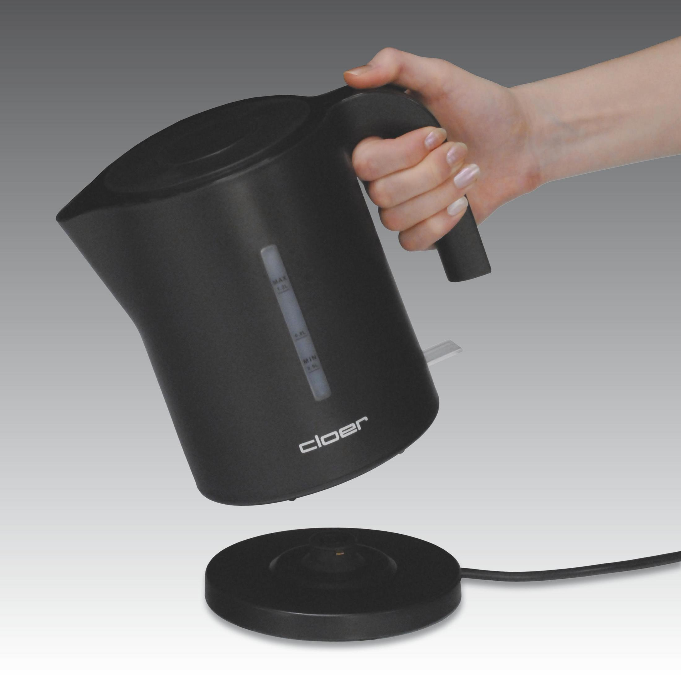 Schwarzer Wasserkocher in der Hand. Er steht auf einer schwarzen Basis, und ein Kabel ist angeschlossen.
