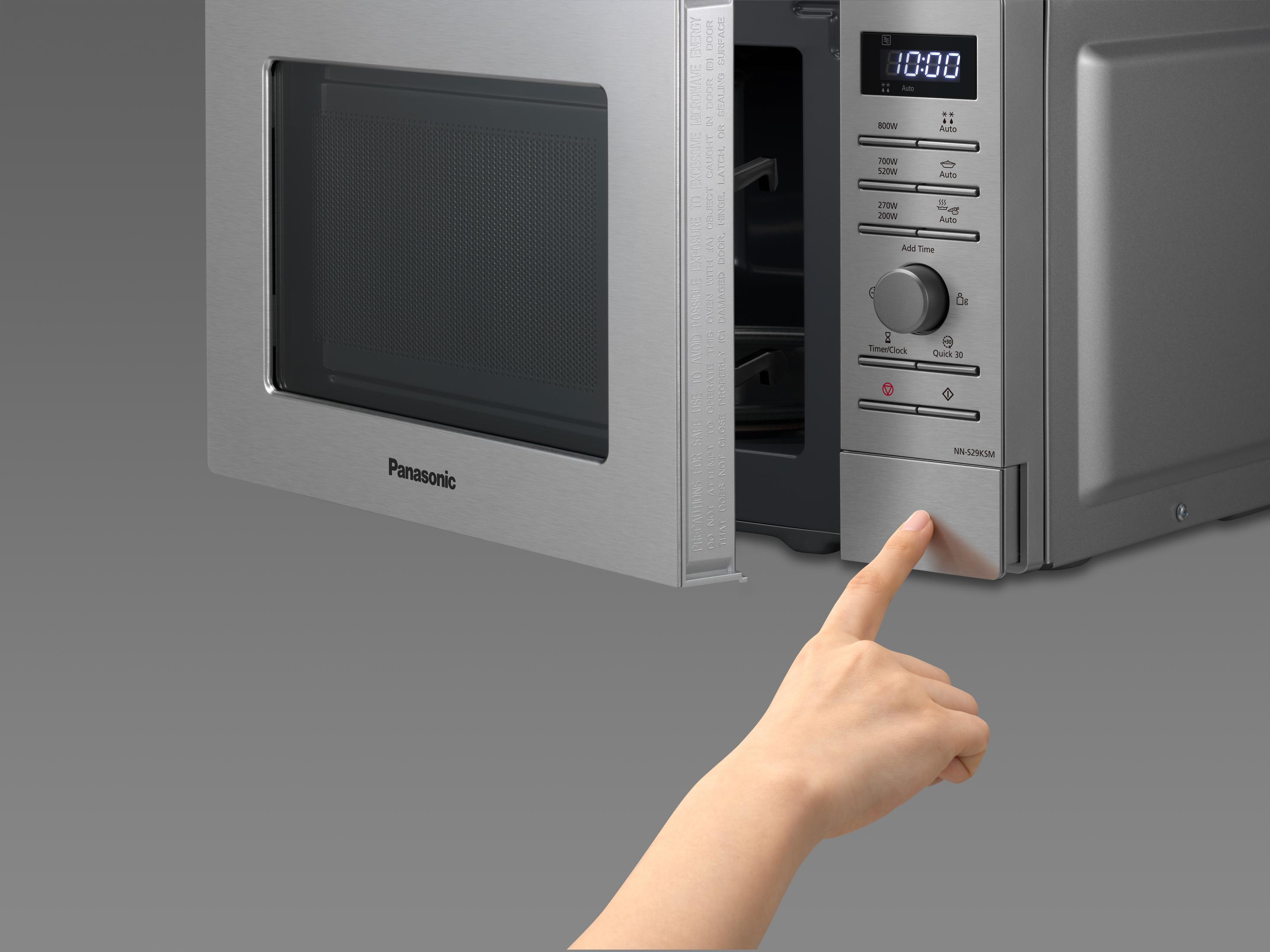 Eine Hand drückt die Öffnungstaste einer Panasonic Mikrowelle.