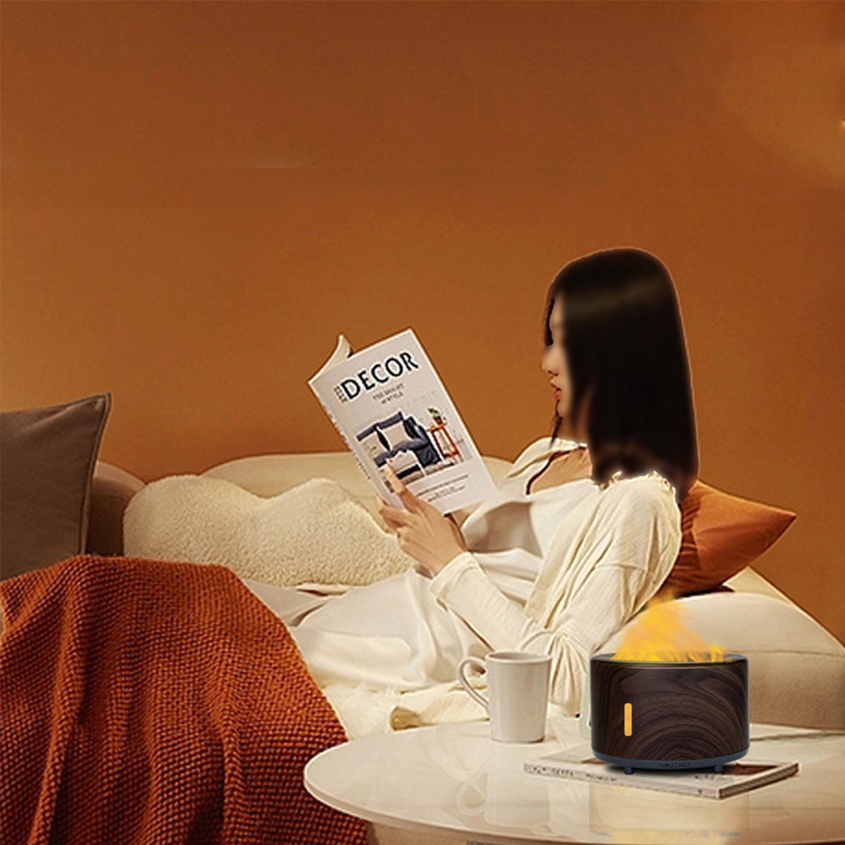 Frau auf einem Sofa, die eine Zeitschrift liest. Ein Diffusor mit Flammeneffekt steht auf dem Tisch.