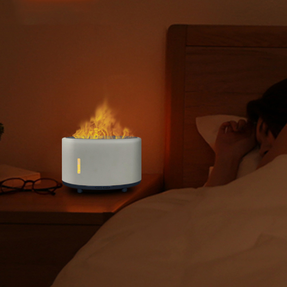 Ein flammenartiges Gerät auf einem Nachttisch, im Hintergrund schläft eine Person.